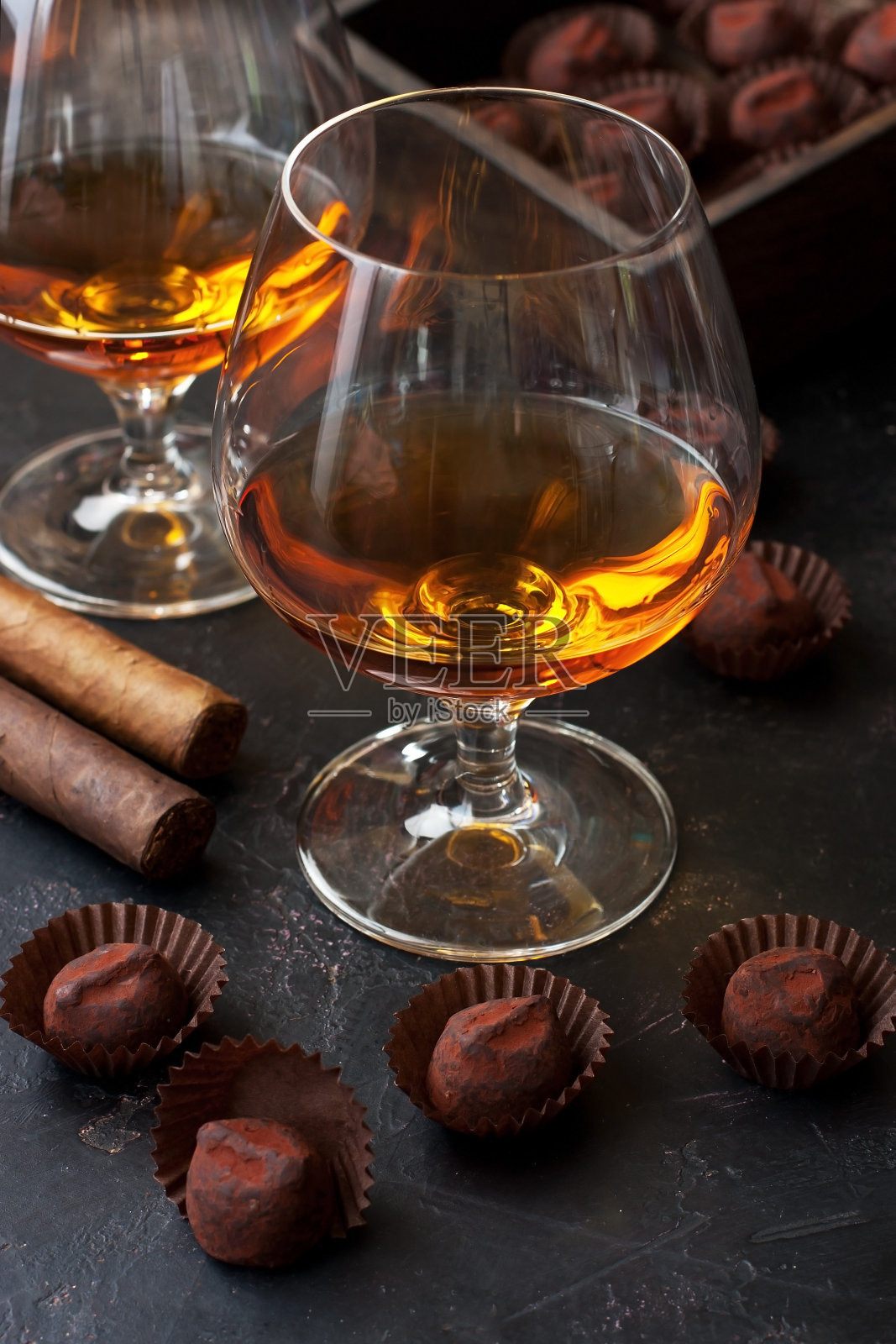 黑色的桌子上放着一杯威士忌、巧克力和雪茄照片摄影图片
