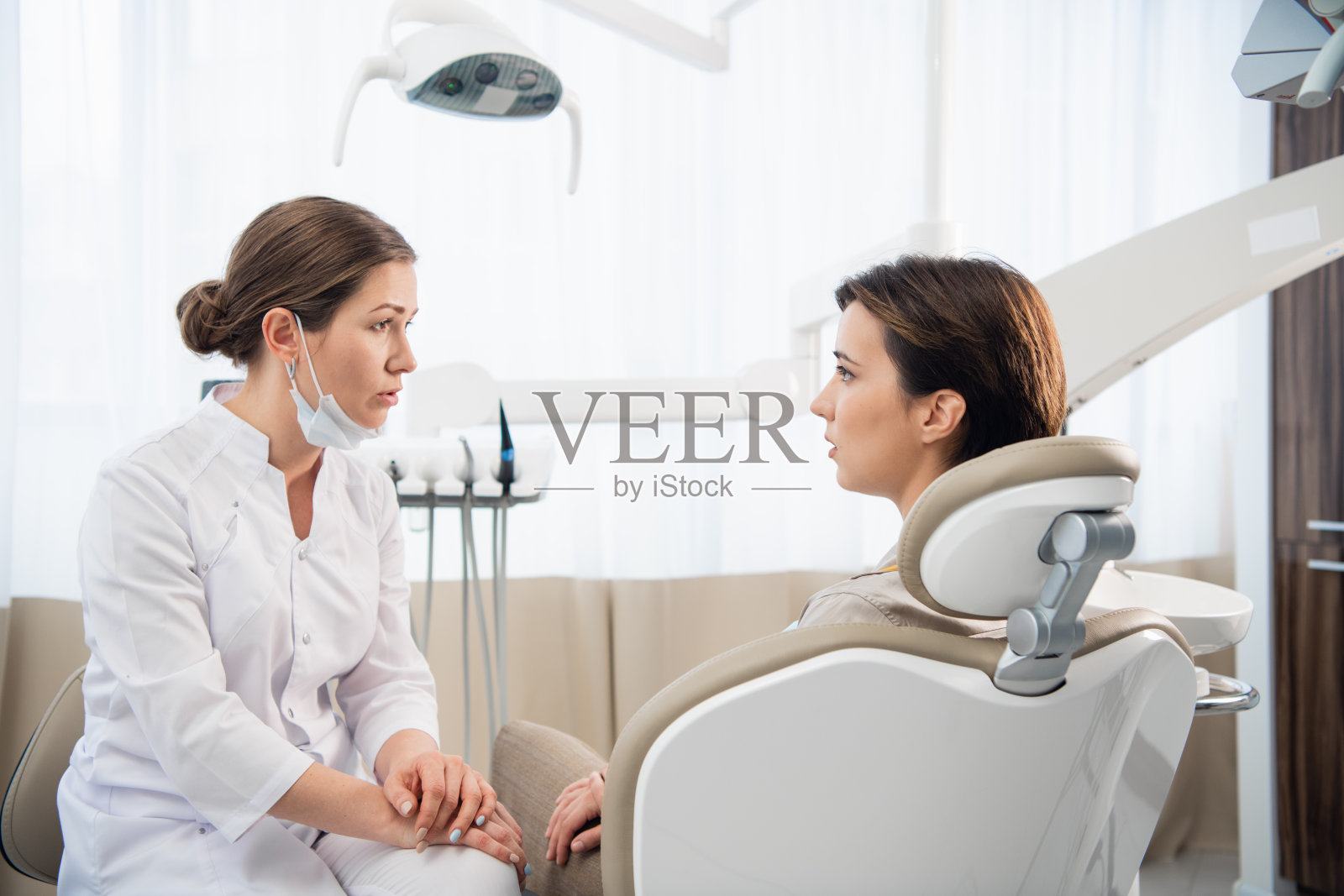 一个年轻的女人向她的医生d解释她的牙齿问题照片摄影图片