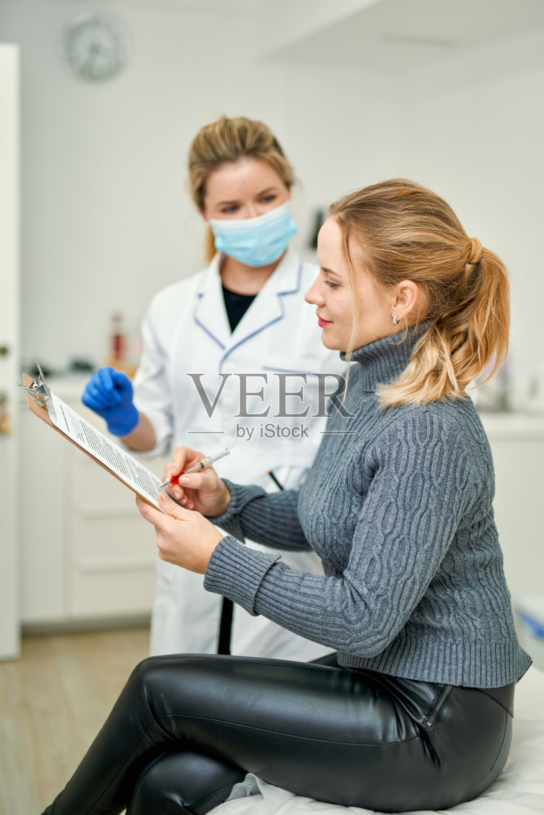 全民大规模接种疫苗。戴口罩的女医生在给患者接种Covid-19抗病毒疫苗前先让患者签署文件照片摄影图片