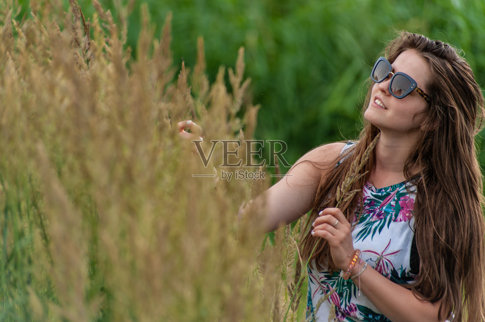 明亮美丽的年轻的黑发女孩戴着太阳镜和夏装在蓝天下享受大自然照片摄影图片