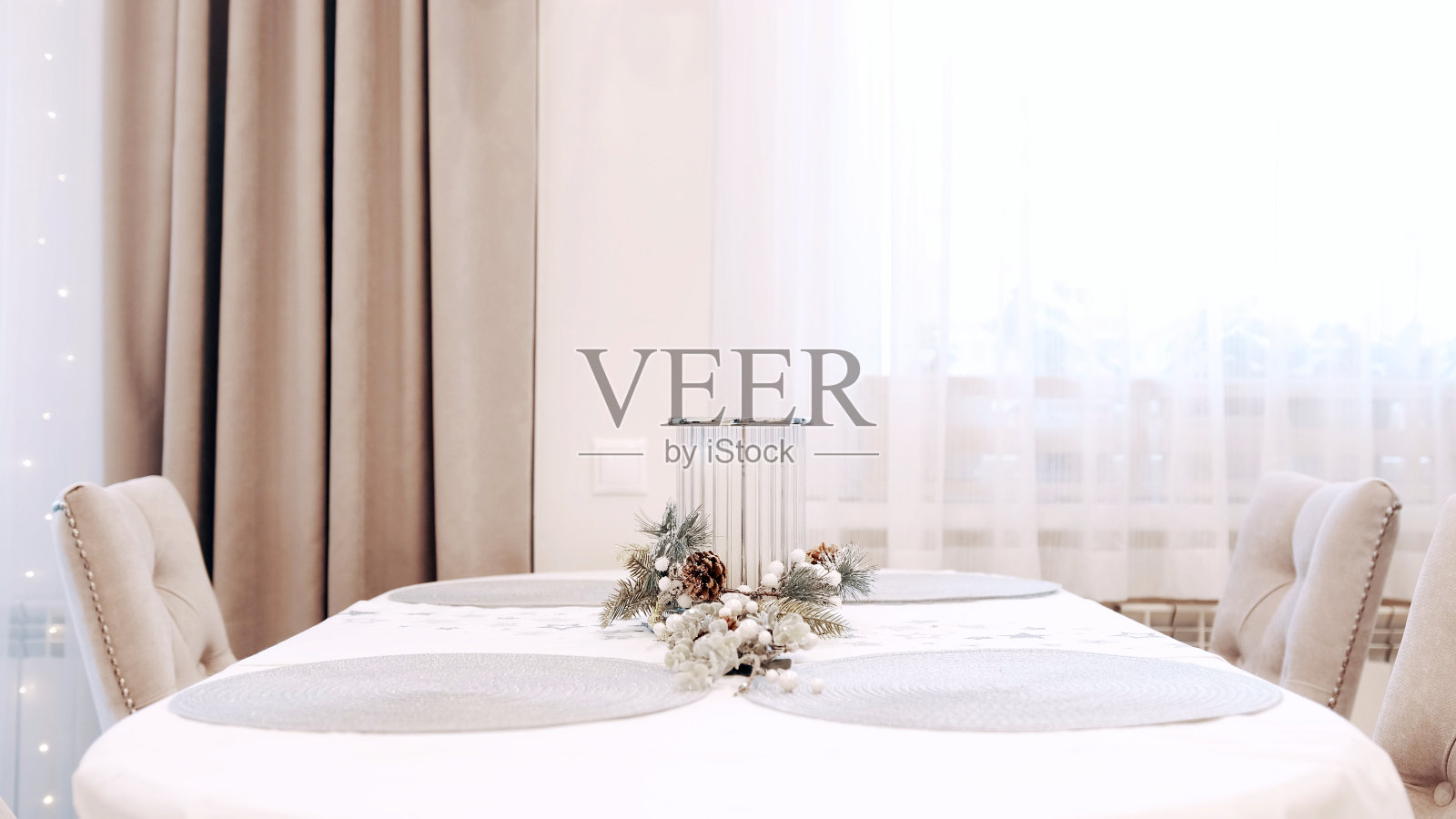 身穿白色连衣裙的黑发女孩在餐桌上放了一支漂亮的圣诞蜡烛照片摄影图片