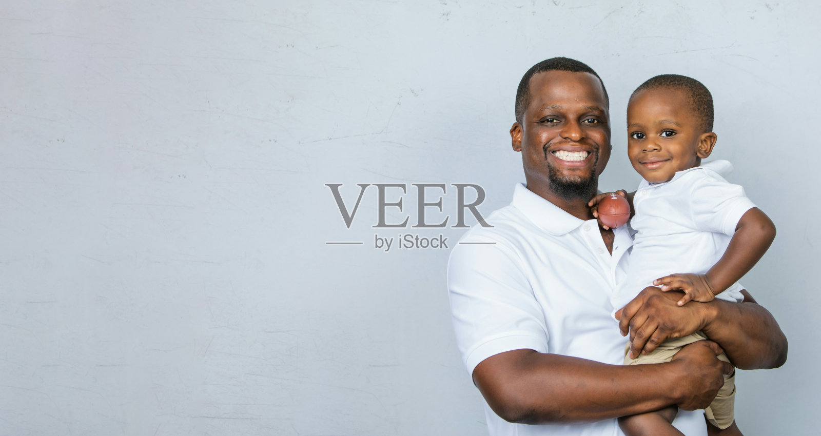 一位英俊的非裔美国父亲抱着他可爱的蹒跚学步的儿子照片摄影图片