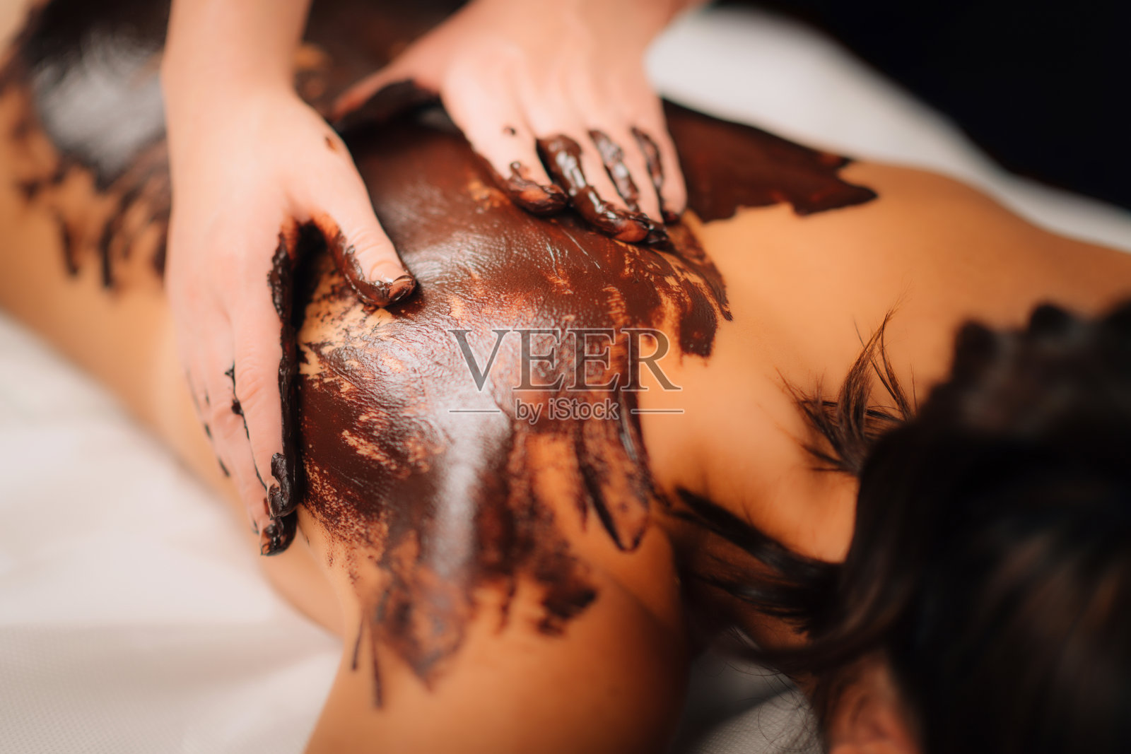 在健康沙龙放松巧克力背部按摩。照片摄影图片
