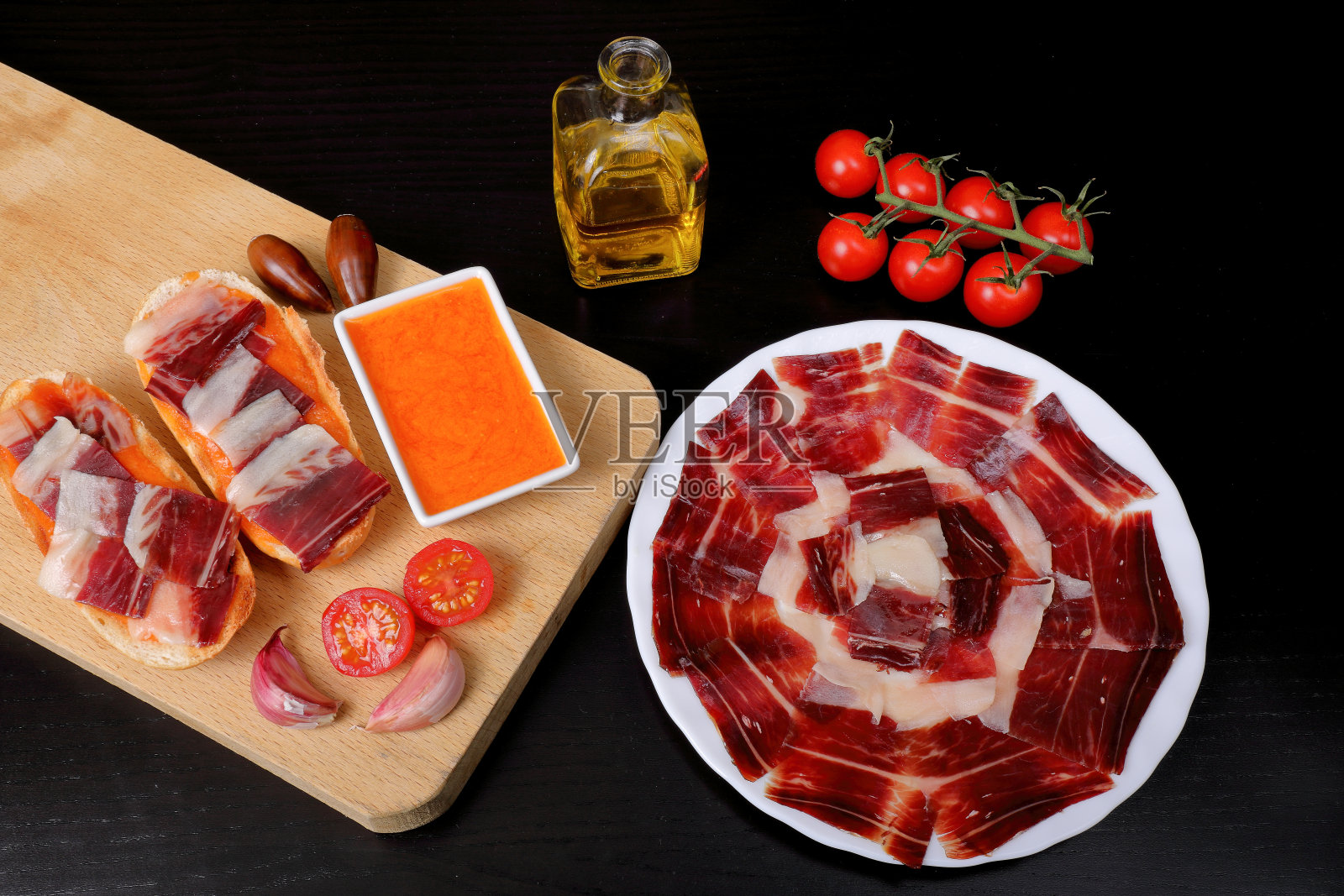 早餐:面包吐司，以橡子喂食的伊比利亚火腿，番茄，大蒜和橄榄油(tumaca面包)，黑色背景照片摄影图片