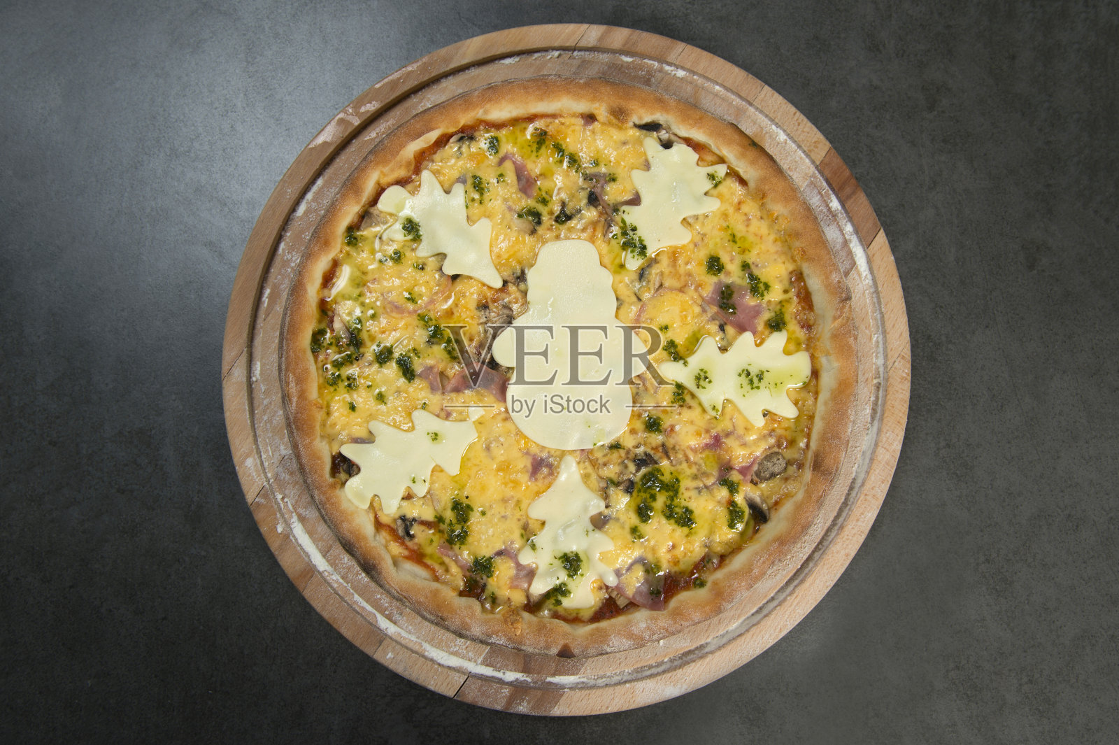 新年披萨配香蒜沙司，背景是深色的石头。披萨上面有一个奶酪雪人的轮廓照片摄影图片