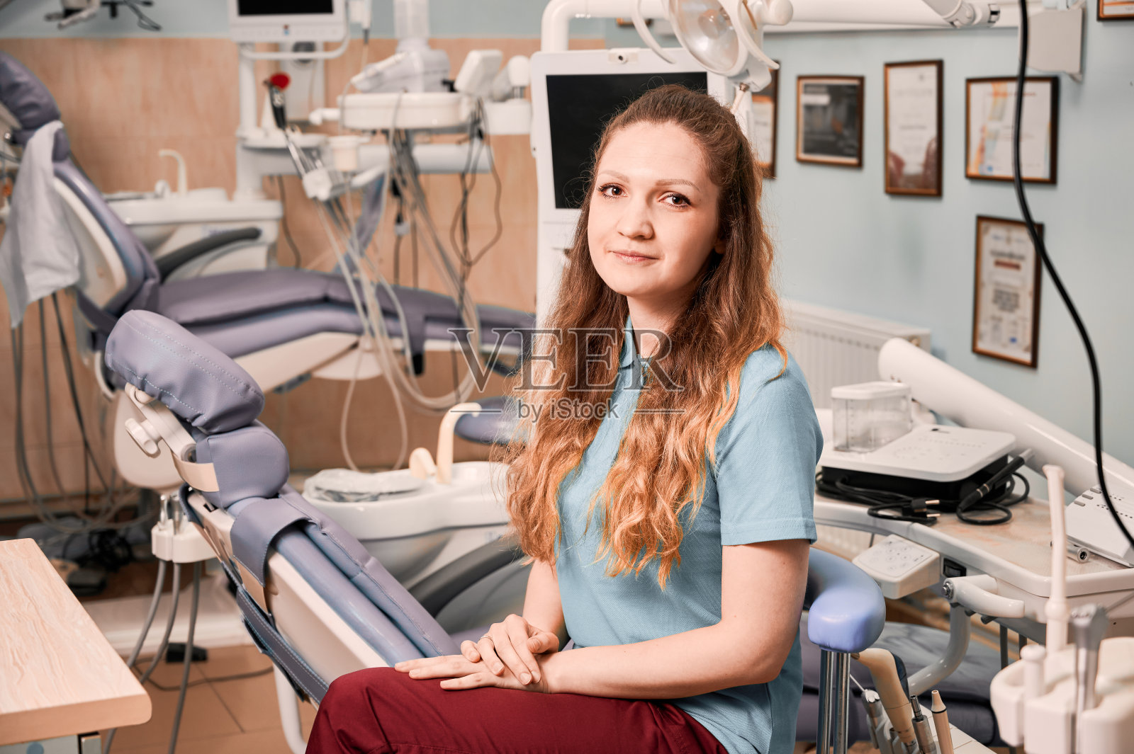 女牙医坐在牙科柜中的椅子上。照片摄影图片