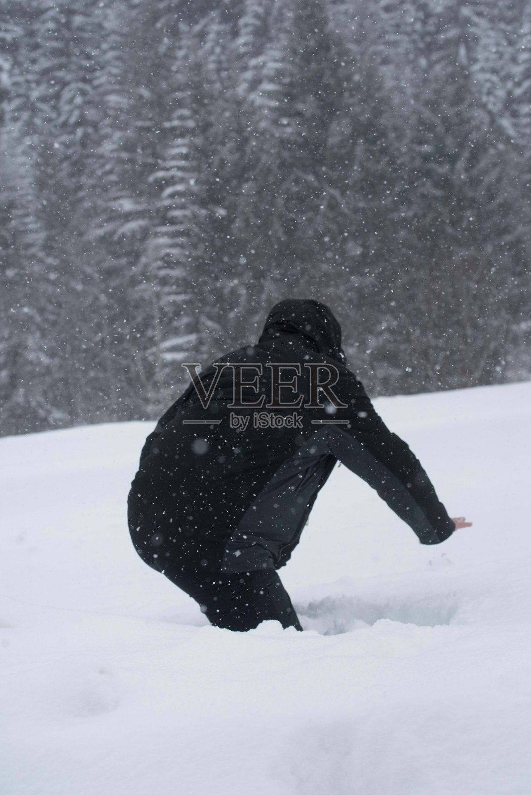 穿着黑色衣服的人走在深深的雪地里照片摄影图片