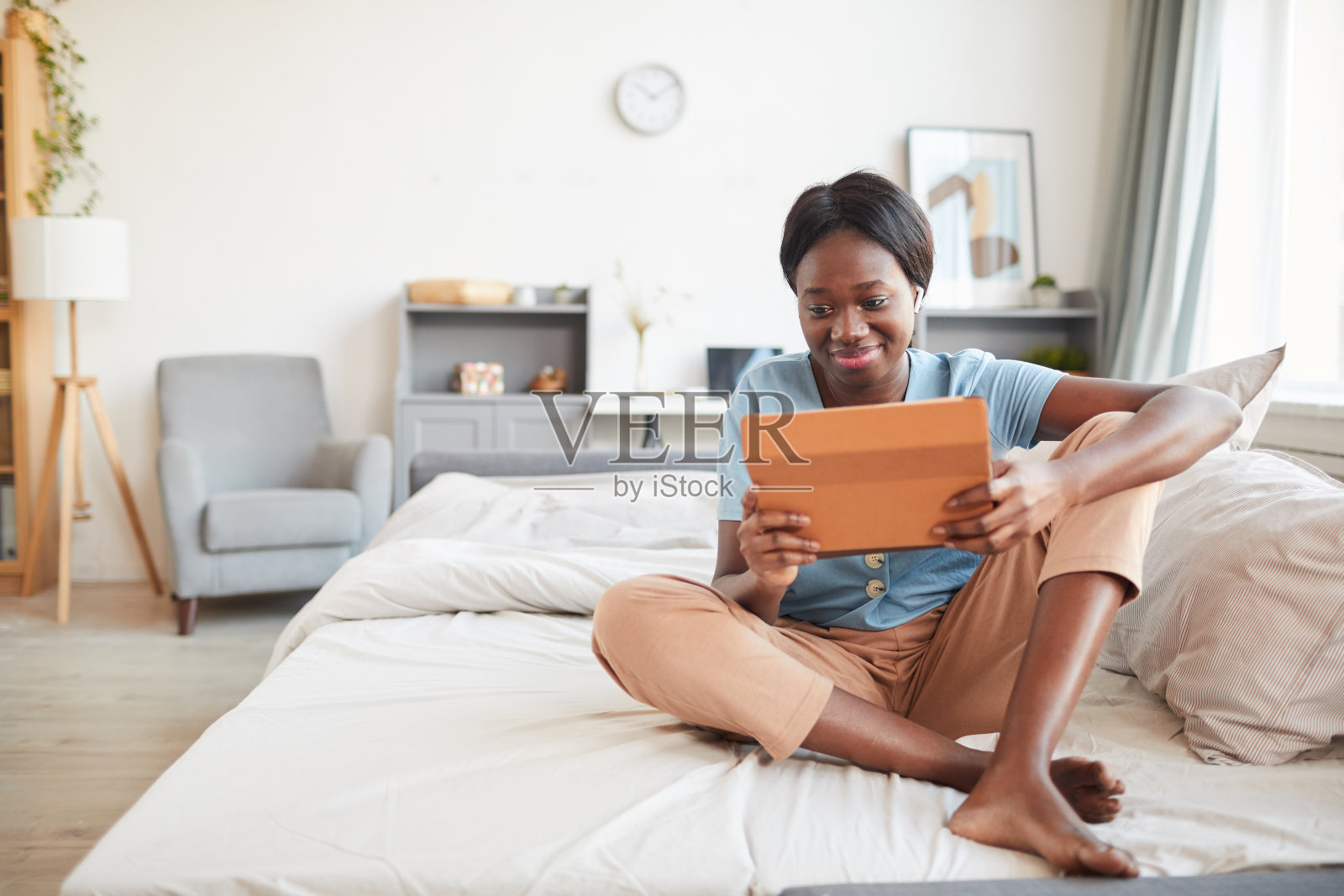 年轻的非裔美国妇女在床上使用平板电脑照片摄影图片