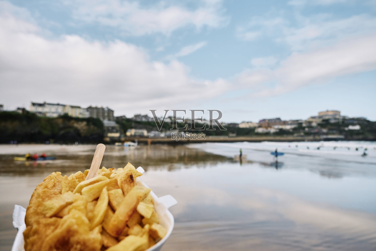 秋天的一天，在康沃尔纽基的托万海滩，一只手拿着一盒炸鱼薯条。照片摄影图片