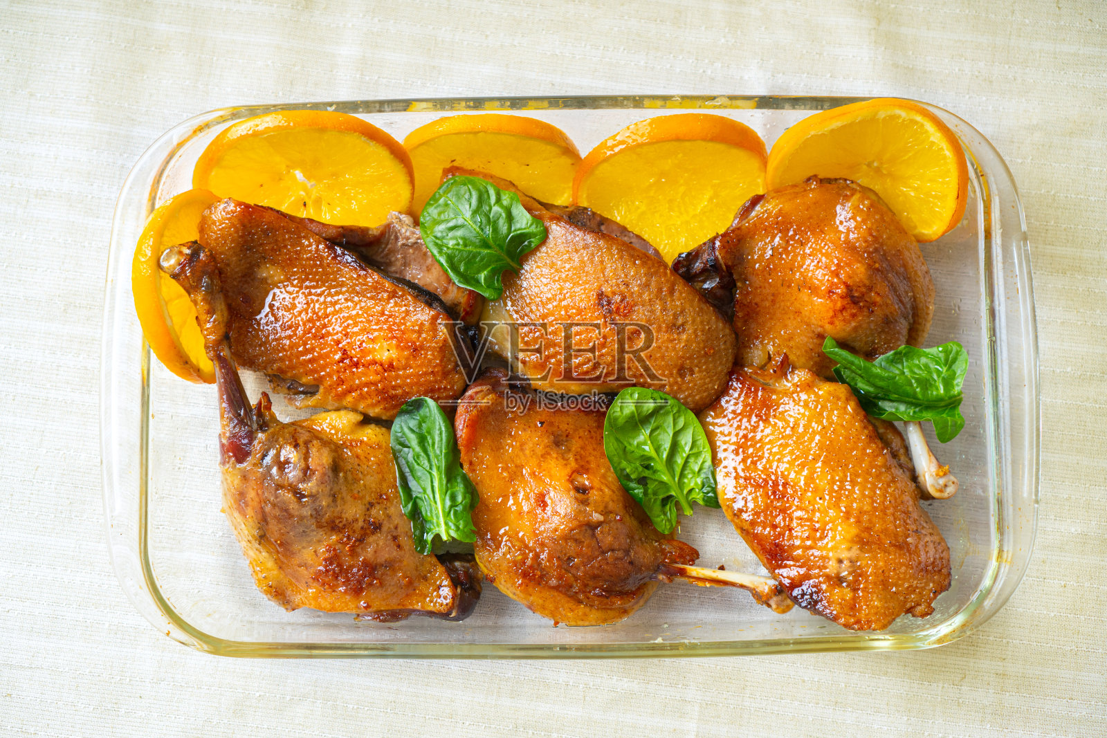 美味的烤鸭腿和柳橙汁。烤鸭肉配橙子和菠菜。前视图。照片摄影图片