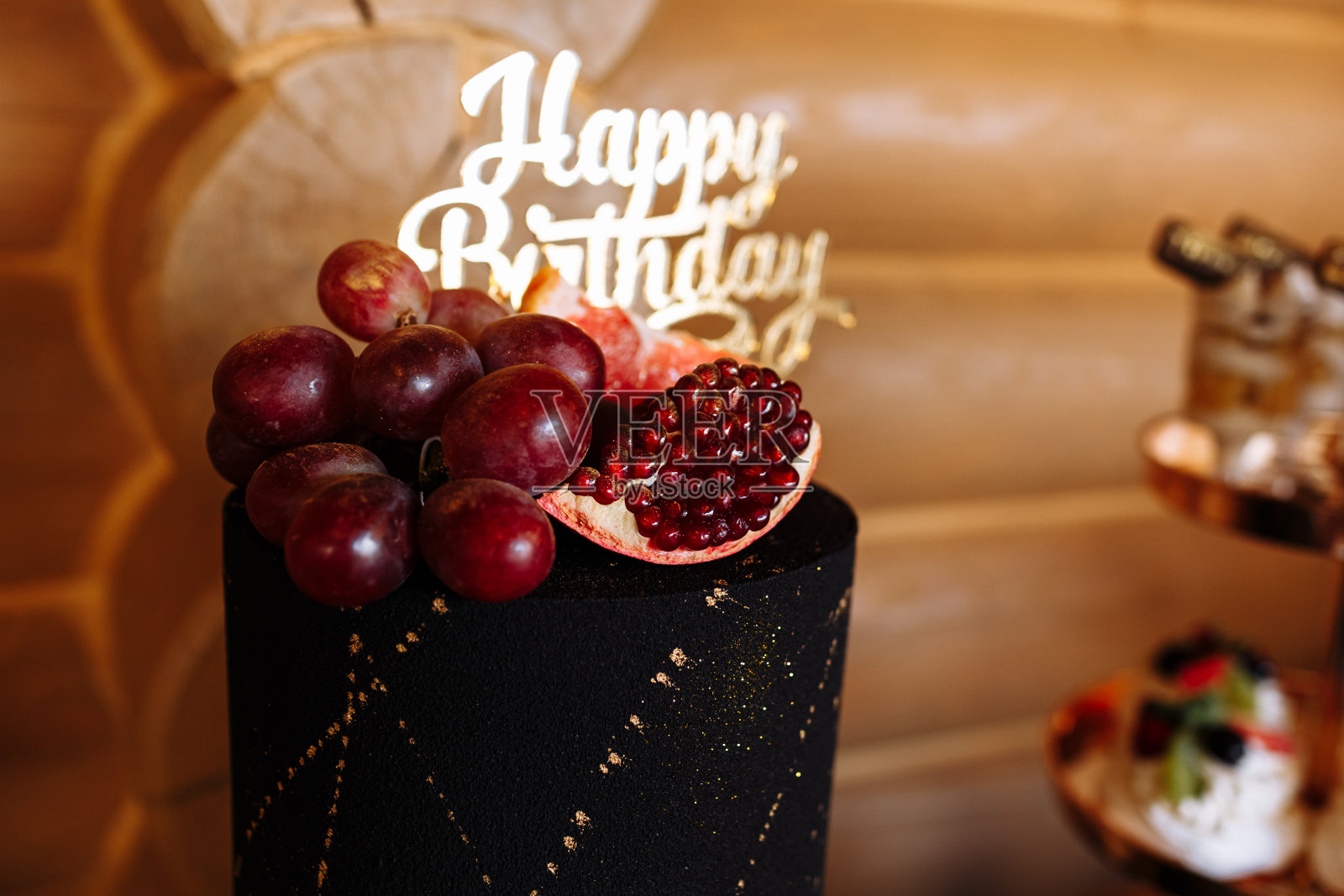 大的黑色生日蛋糕，新鲜的水果和糖果放在节日的桌子上。糖果酒吧。餐桌上有各种各样的糖果照片摄影图片