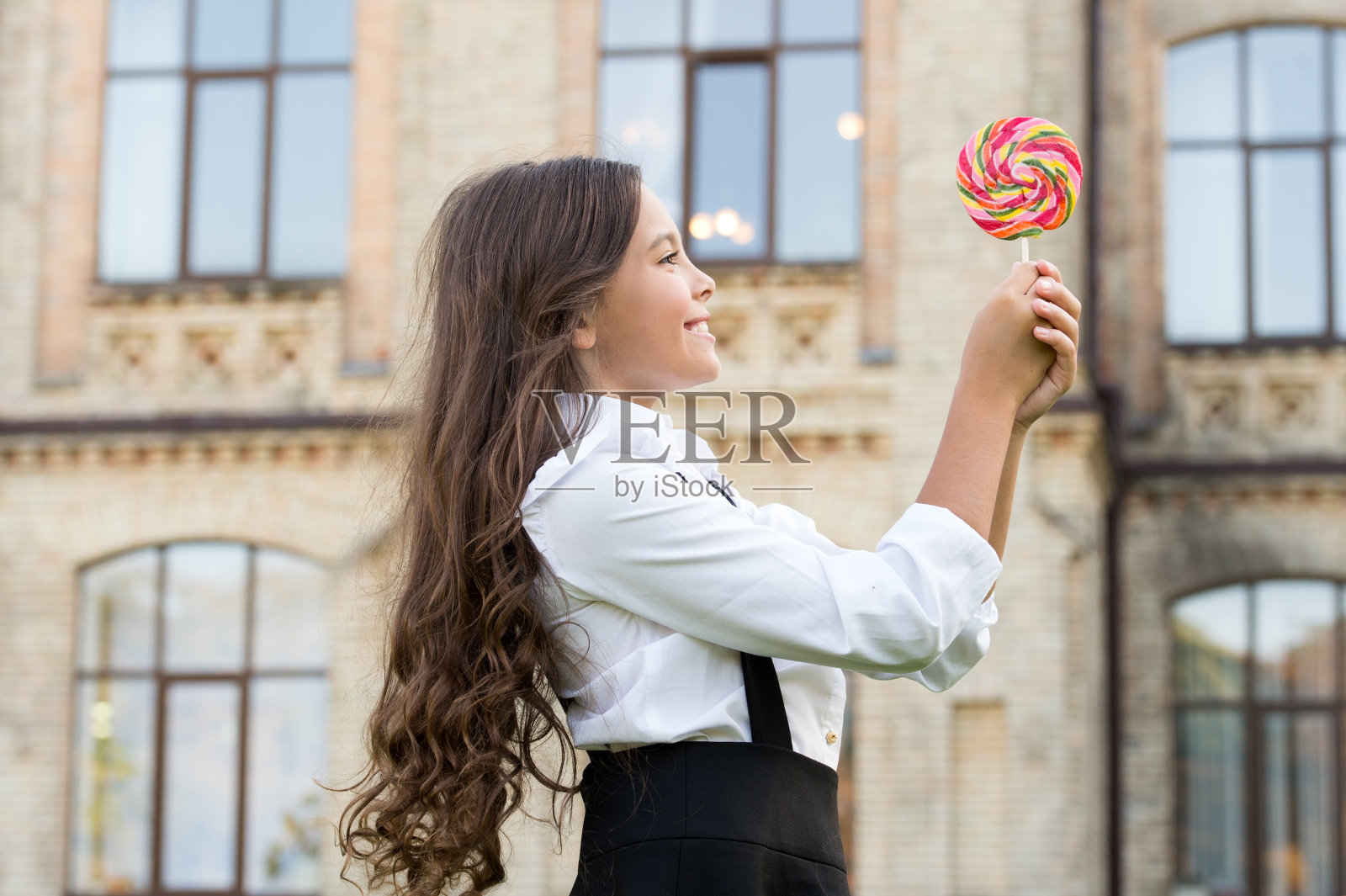 快乐的孩子和糖果。快乐的童年。一个小孩在户外拿着棒棒糖。快乐的孩子在户外玩糖果。学校营养。热量和能量。女生应该甜点照片摄影图片