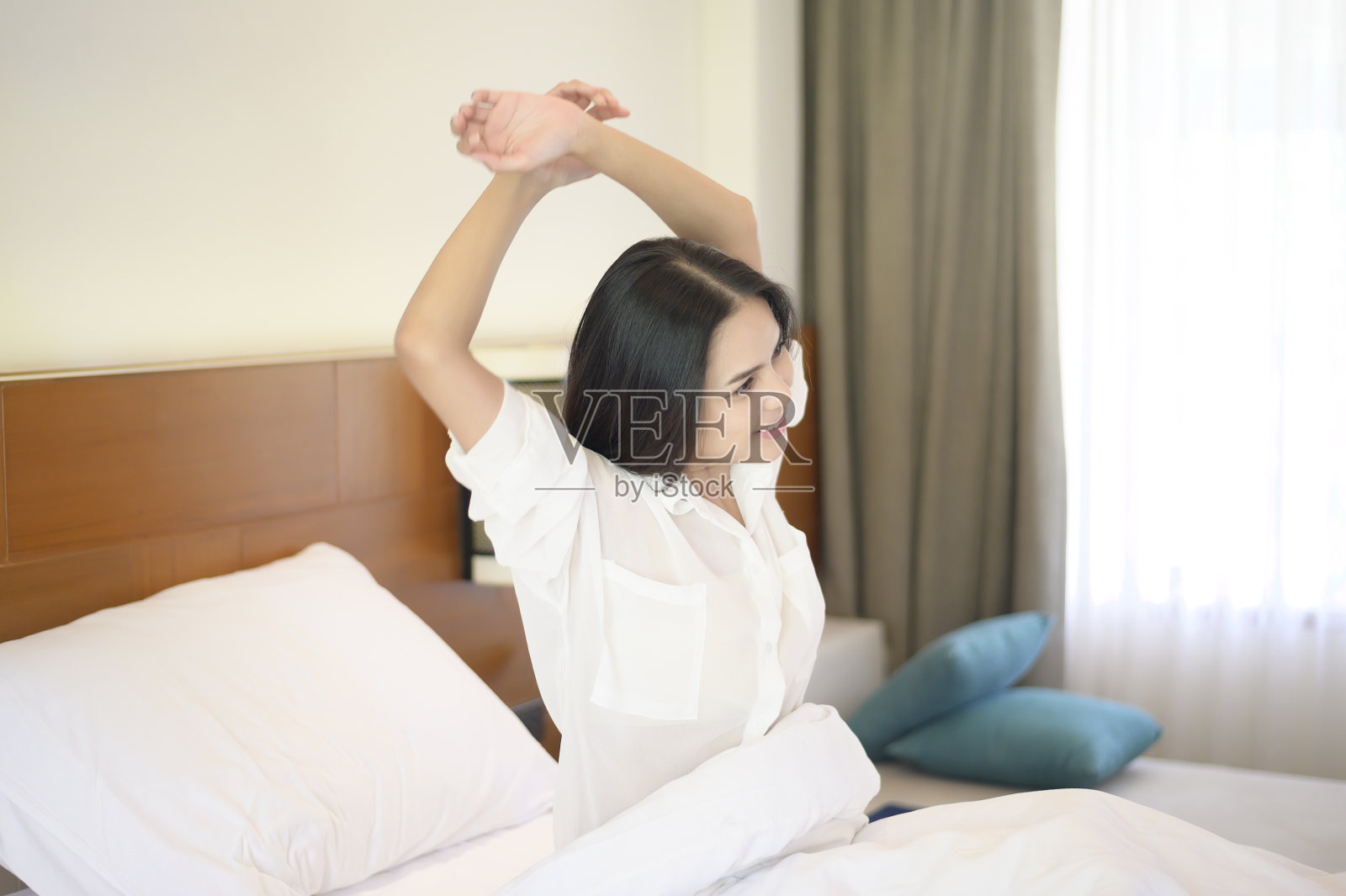 清晨在家醒来后，一个面带微笑的女人伸开双手。照片摄影图片