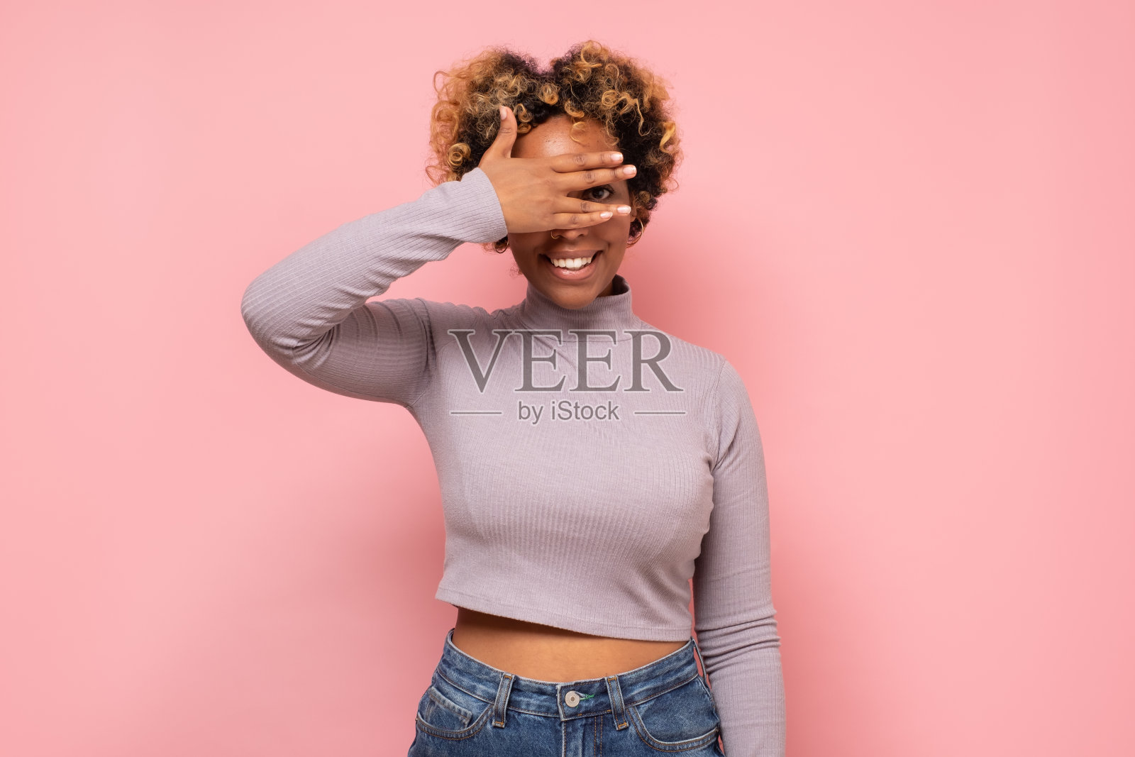 微笑年轻的非洲裔美国女孩用手遮住脸，偷窥和微笑。照片摄影图片