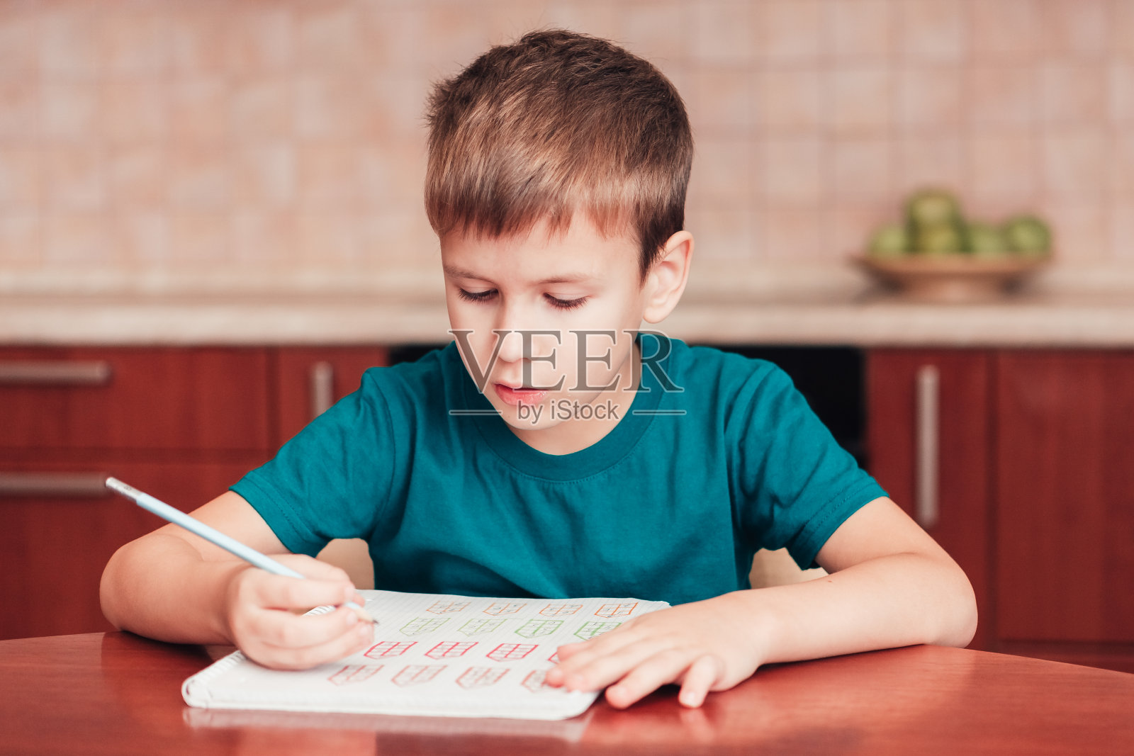 可爱的男生坐在厨房的桌子旁做作业学习数学照片摄影图片