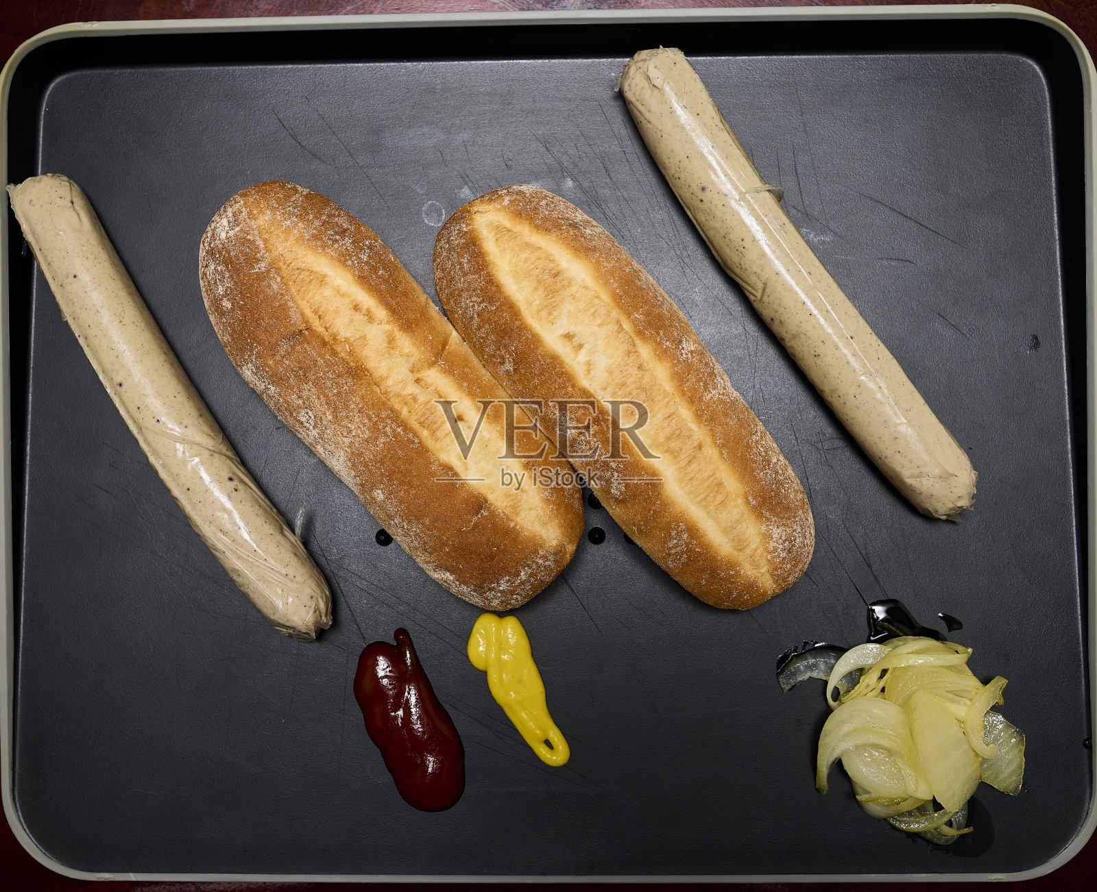 盘子里有两个热狗，蕃茄，芥末和洋葱照片摄影图片