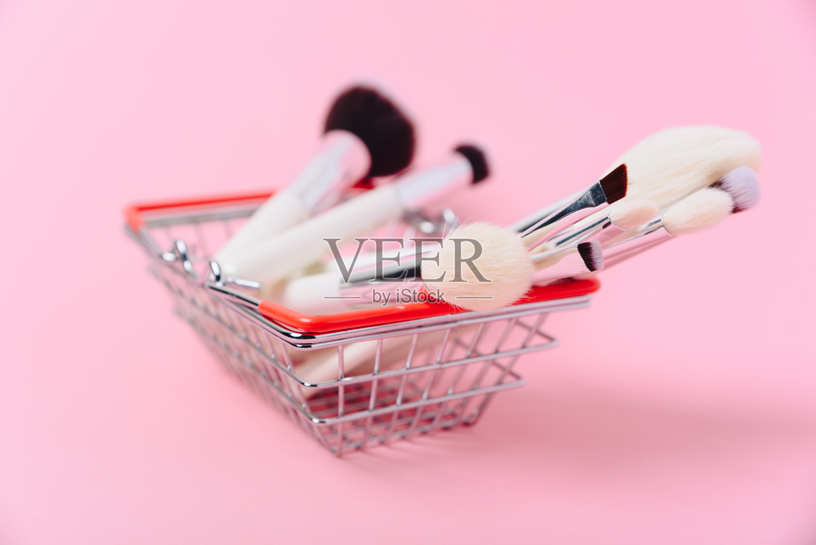化妆刷在一个粉红色的背景篮近距离照片摄影图片