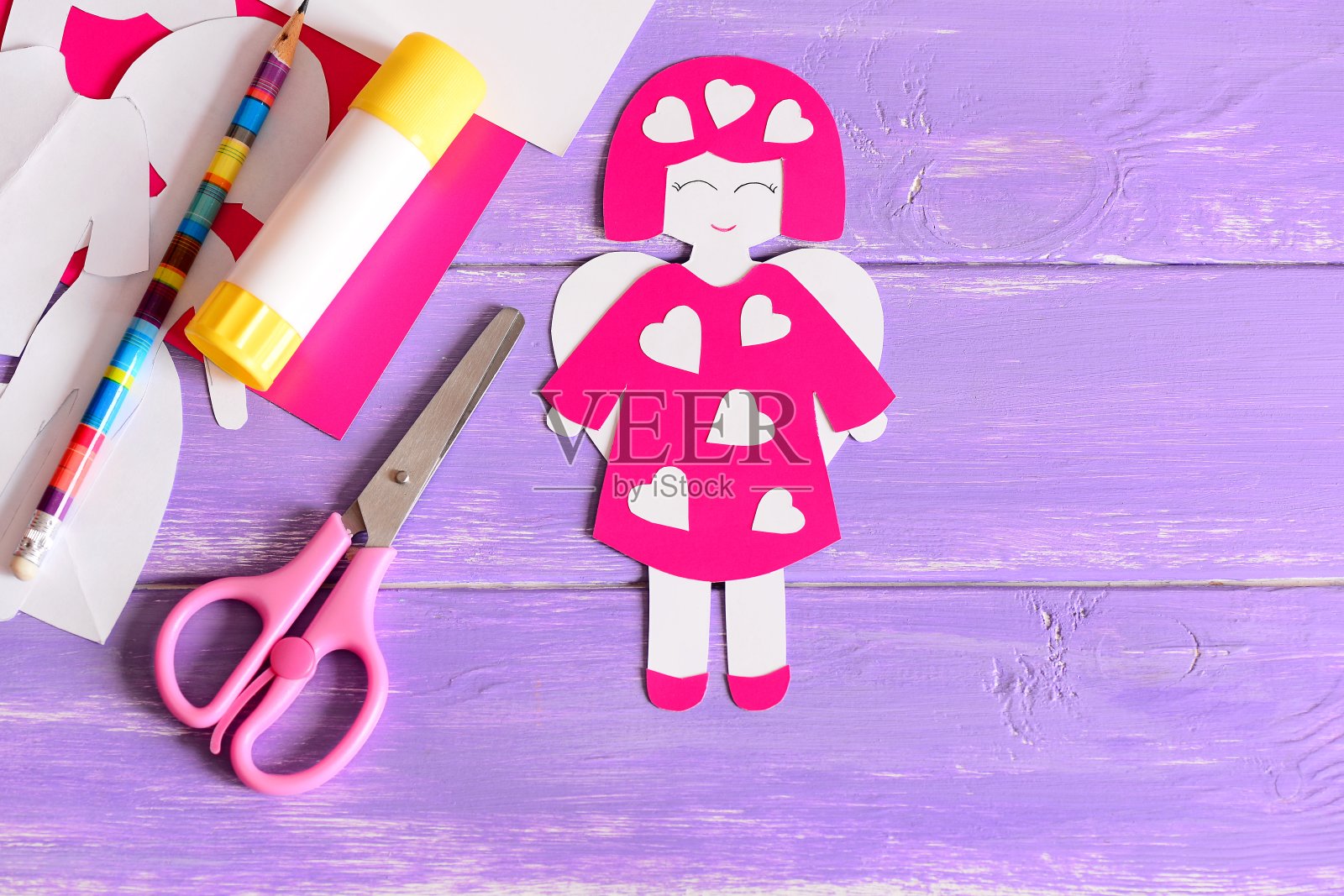 可爱的情人节天使丘比特心形工艺品从纸，剪刀，胶水，纸板，纸模板在紫色木制背景与空白的地方为文本。孩子们为情人节制作的简单工艺品。俯视图照片摄影图片