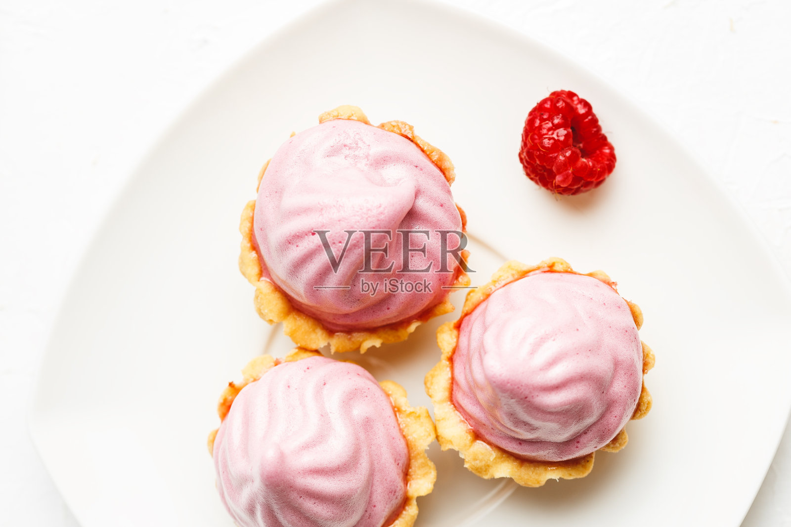 白色盘子上有覆盆子奶油的迷你蛋糕篮照片摄影图片