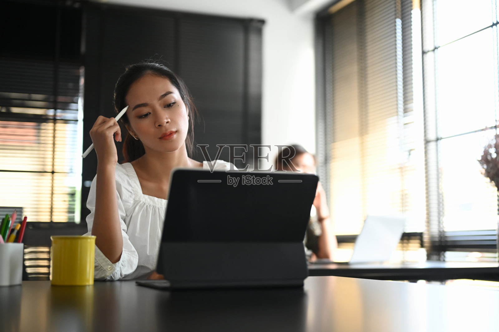 有吸引力的女人思考项目进展和分析信息的平板电脑在工作场所。照片摄影图片