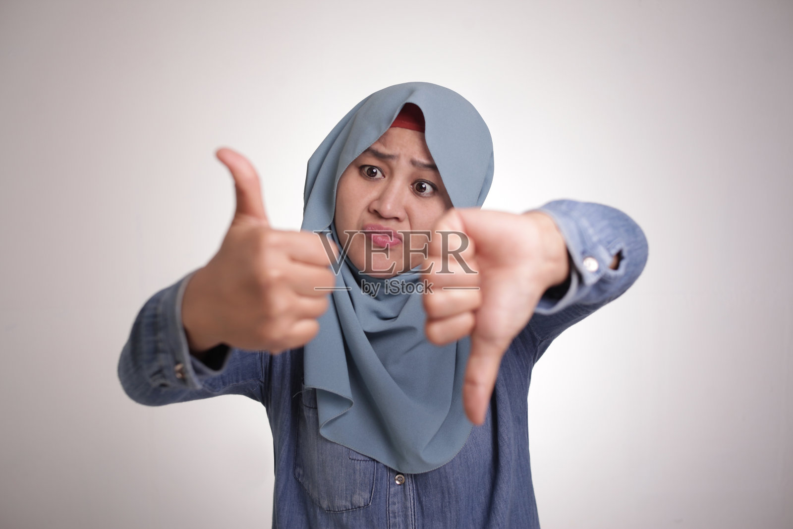 穆斯林妇女做出竖起和放下拇指的手势照片摄影图片
