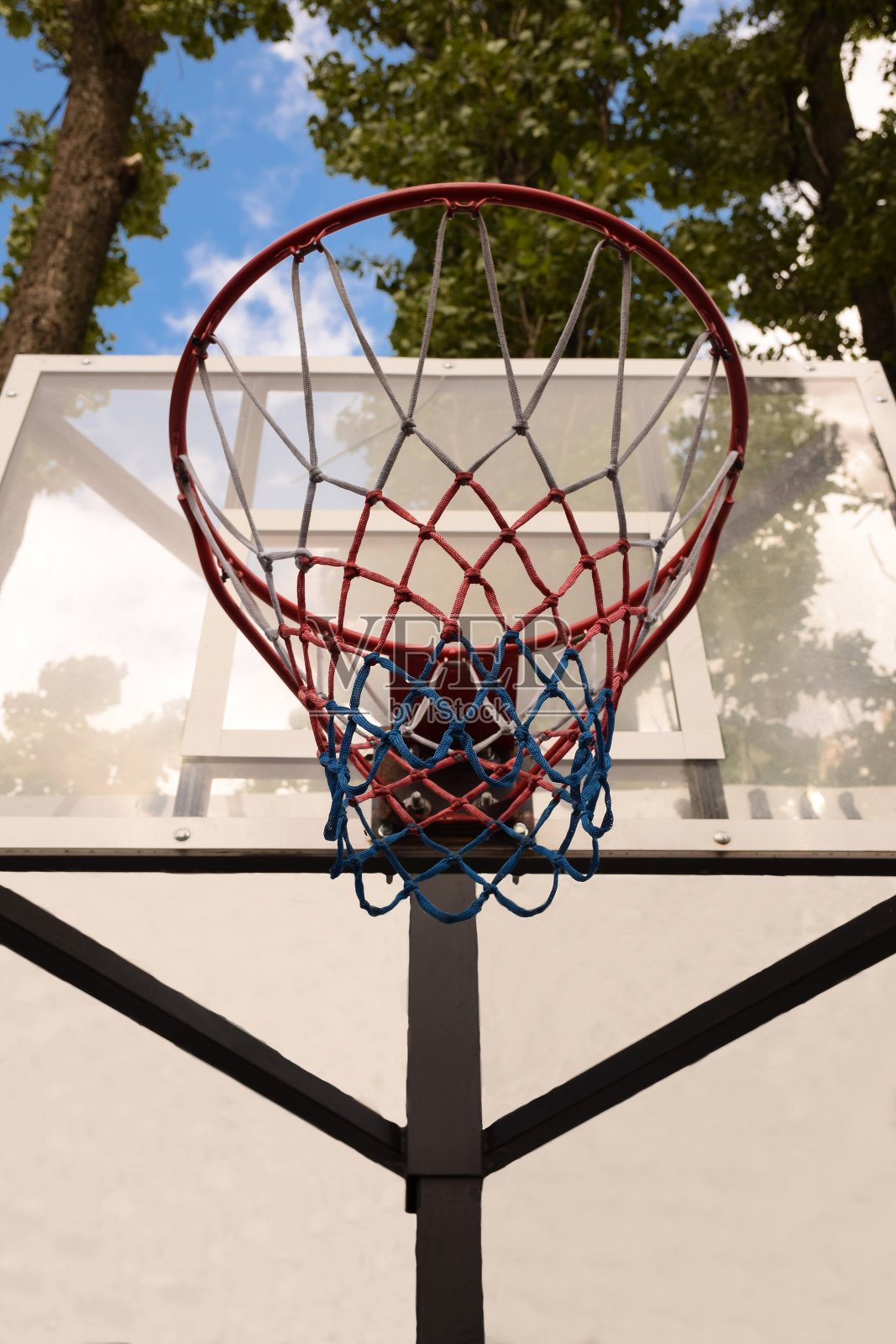 篮筐和篮板在蓝天白云和树木的背景下照片摄影图片