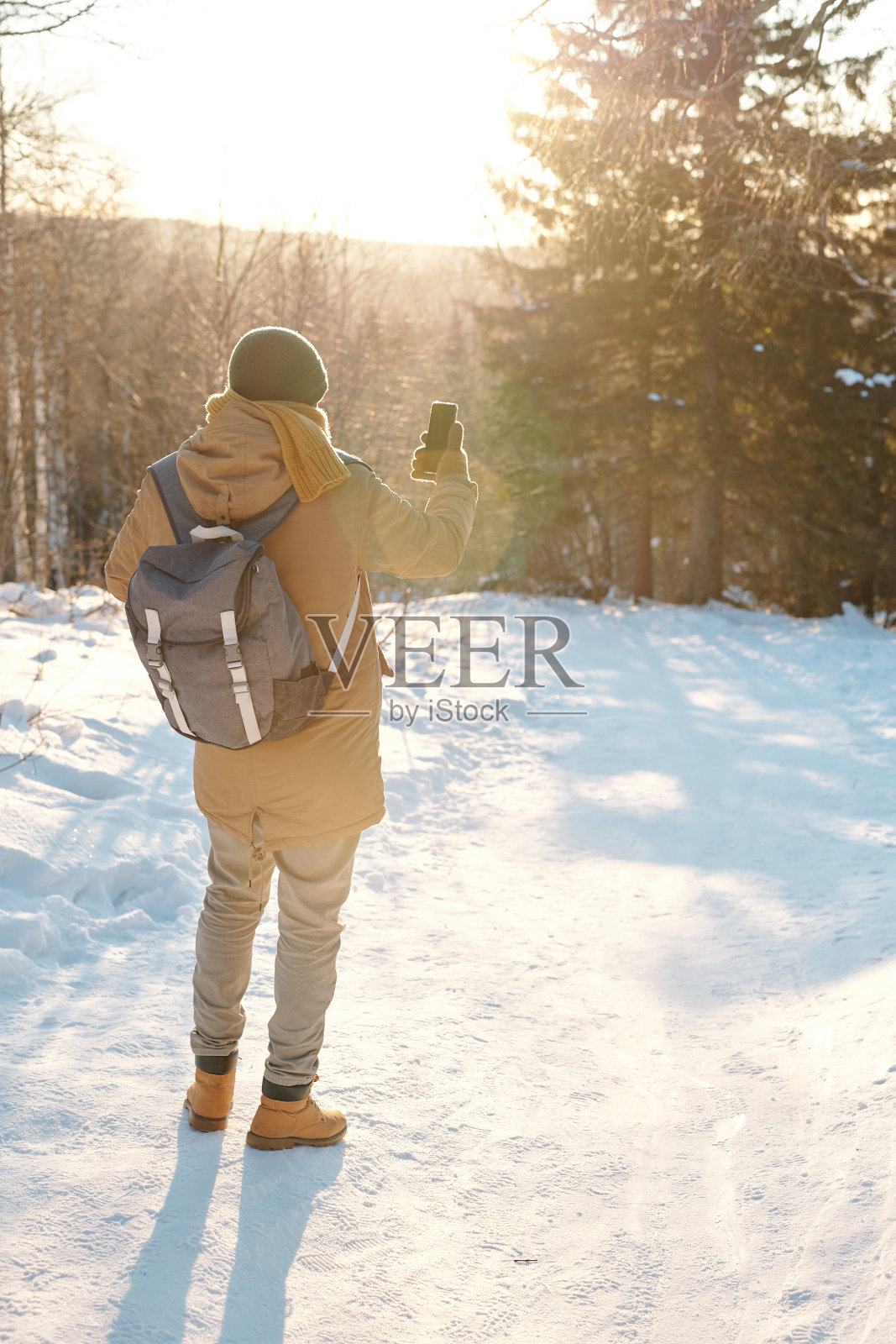 年轻男性背包客在冬天的森林里穿着冬装自拍的背影照片摄影图片