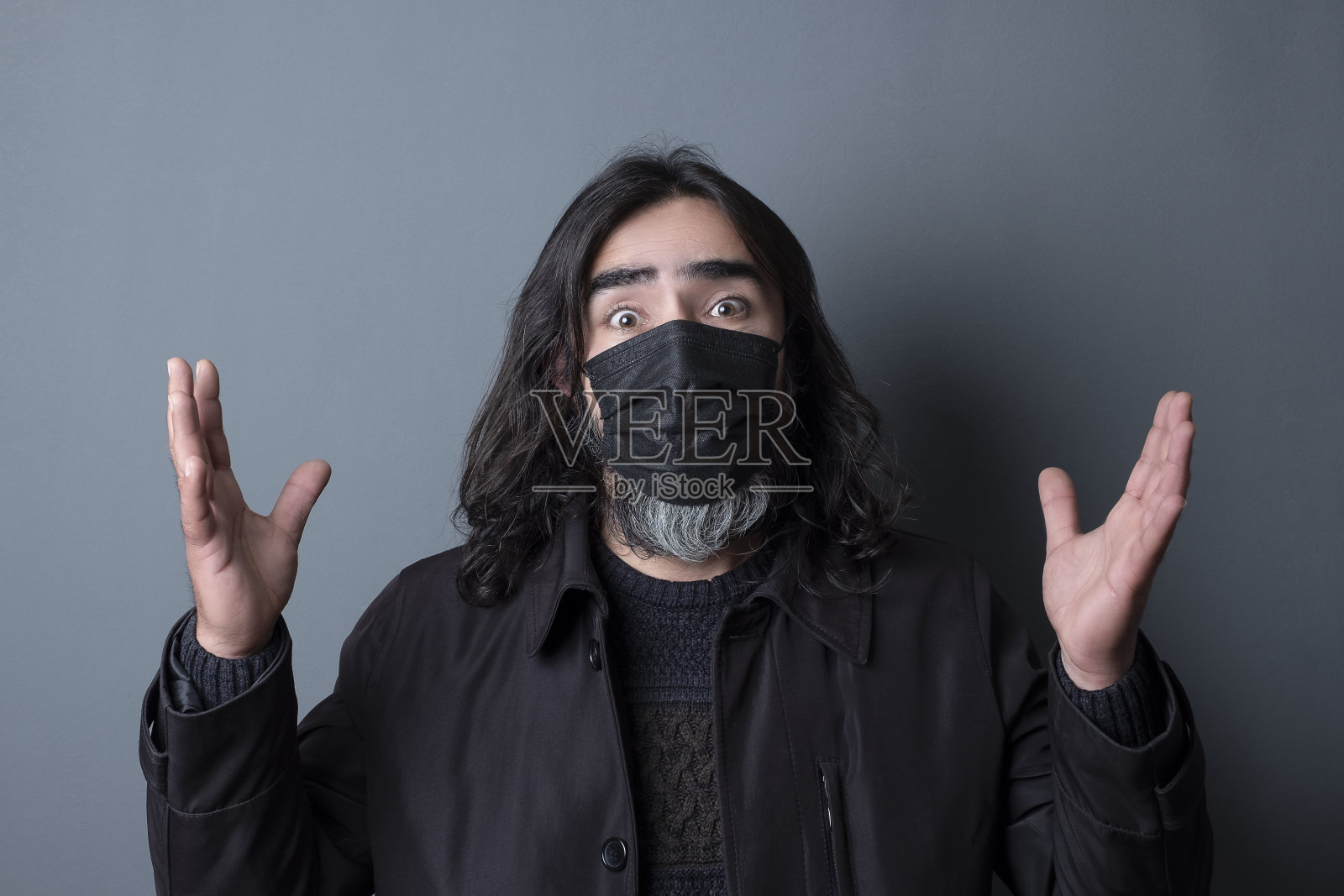 戴着黑色面具的困惑男子双手举在空中照片摄影图片