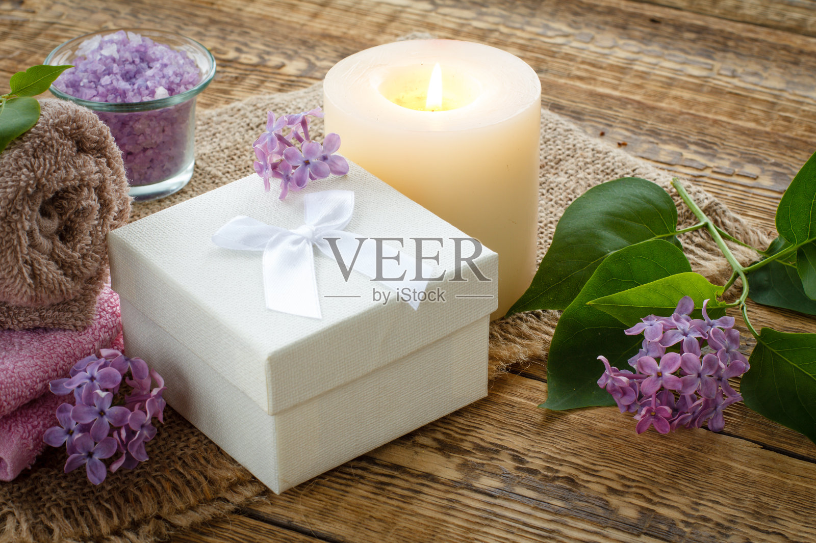 毛巾，礼盒，蜡烛和丁香花木制背景。照片摄影图片