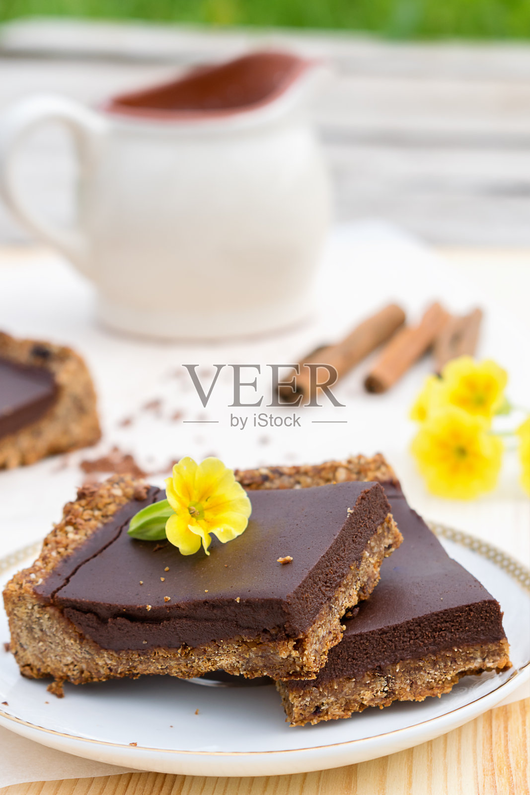 Сhocolate由燕麦，椰奶，黄油，枣和杏仁制成的蛋挞，放在一个白色的碟子上。白色背景中的肉桂枝和黄花。Сoncept的健康食品和健康甜点照片摄影图片