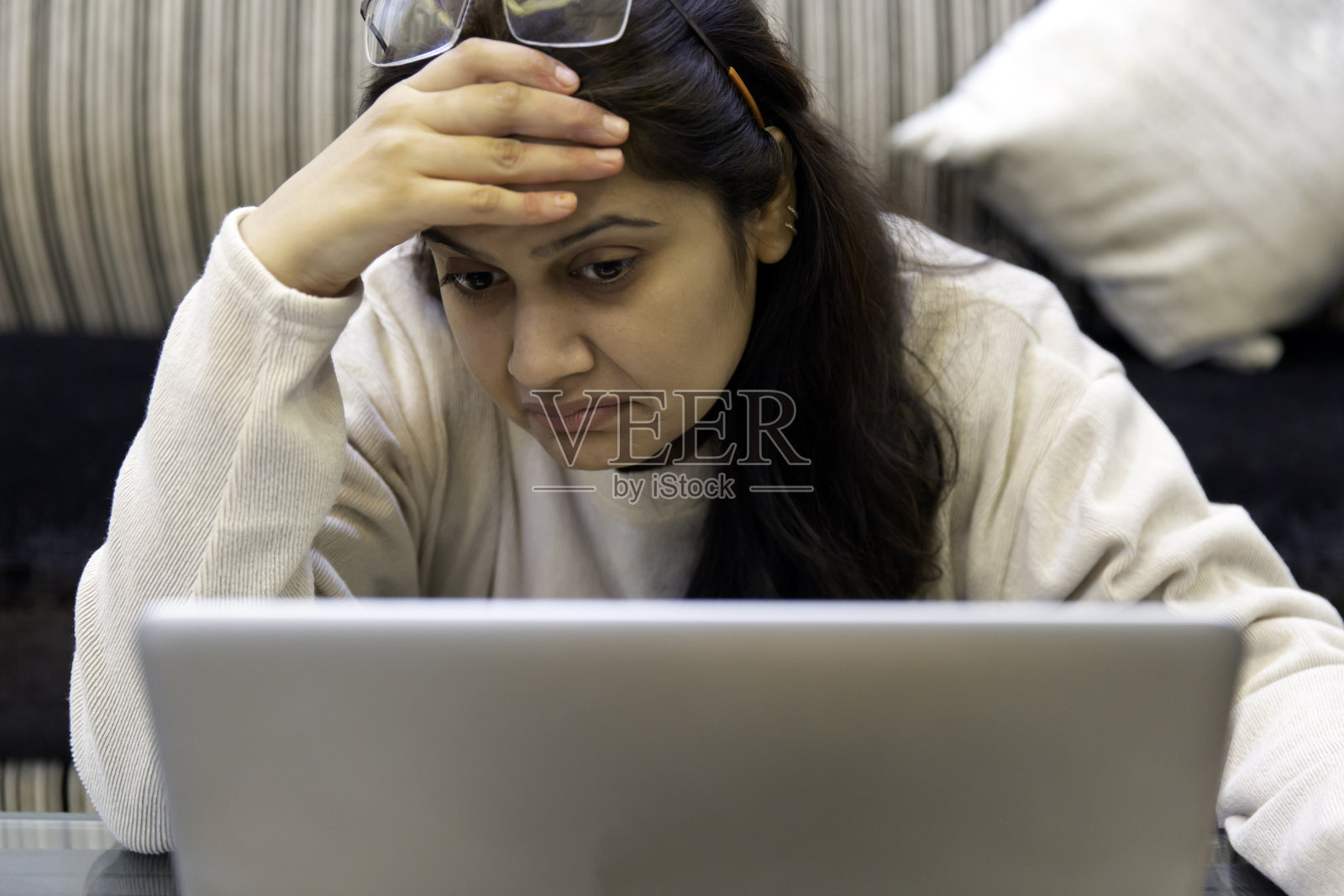 沮丧的印度妇女抓住她的头看笔记本电脑。选择性地关注脸部。教育、金融、商业概念照片。照片摄影图片