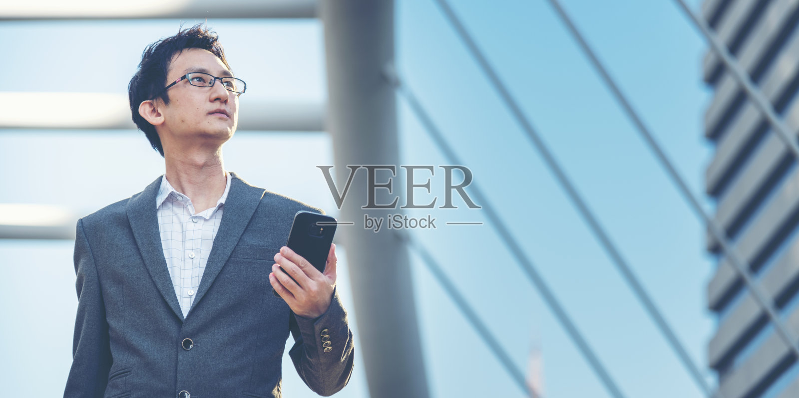 商人手握手机户外冲浪上网在线技术生活在城市街道。年轻企业家西装革履手用智能手机小玩意发短信生活方式照片摄影图片