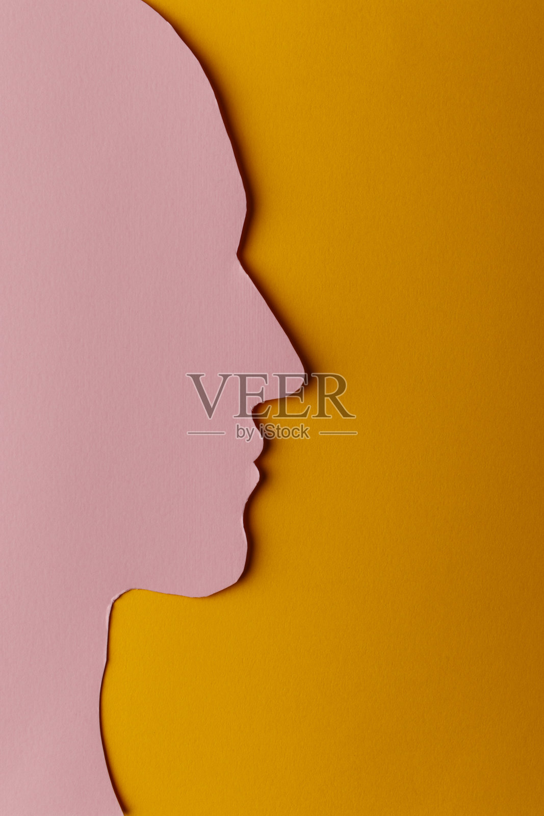 纸做的头像剪影。粉红色的纸，形状像一个人的头，黄色的纸背景上有拷贝空间。照片摄影图片