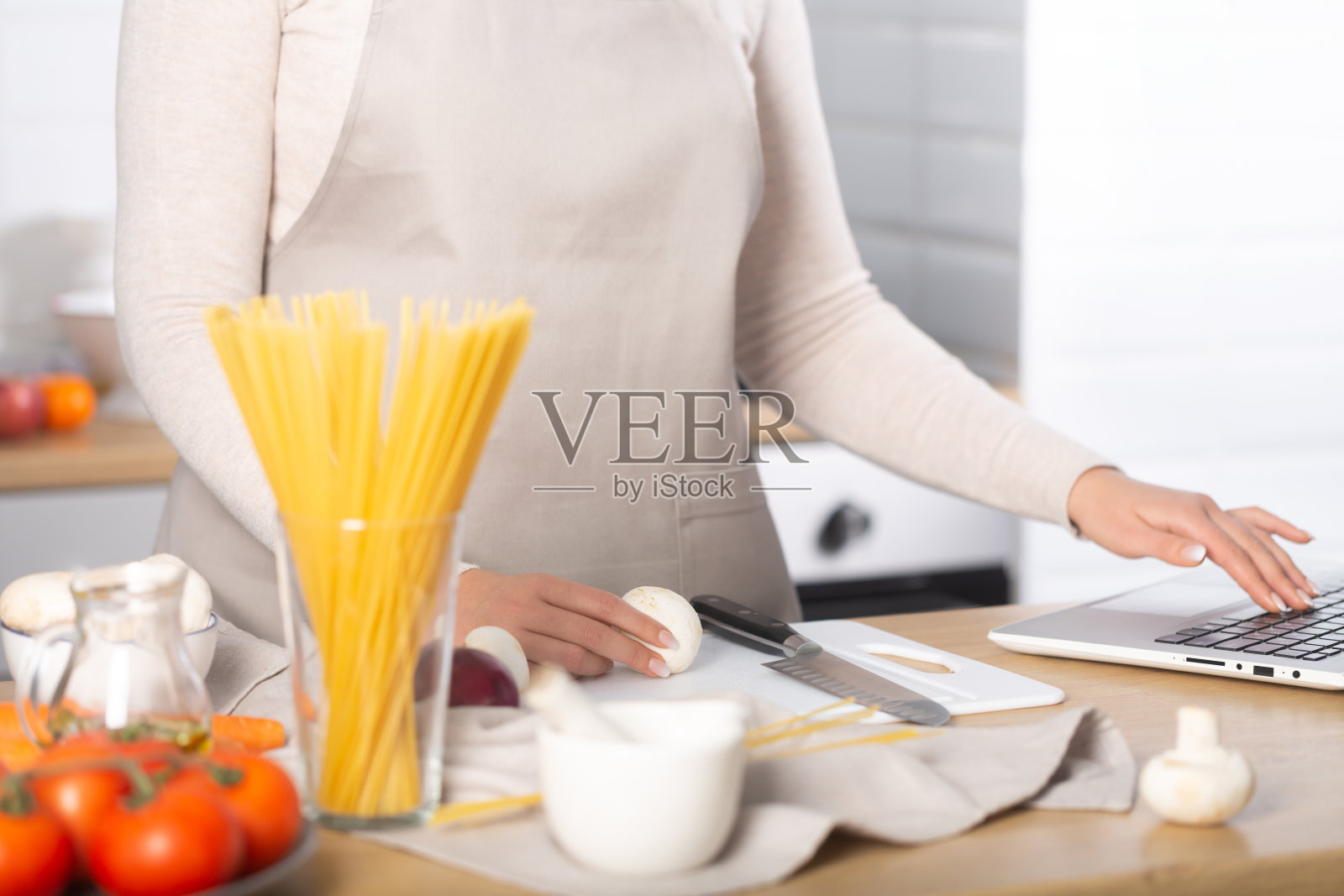 用电脑看虚拟烹饪课的女人做意大利面照片摄影图片