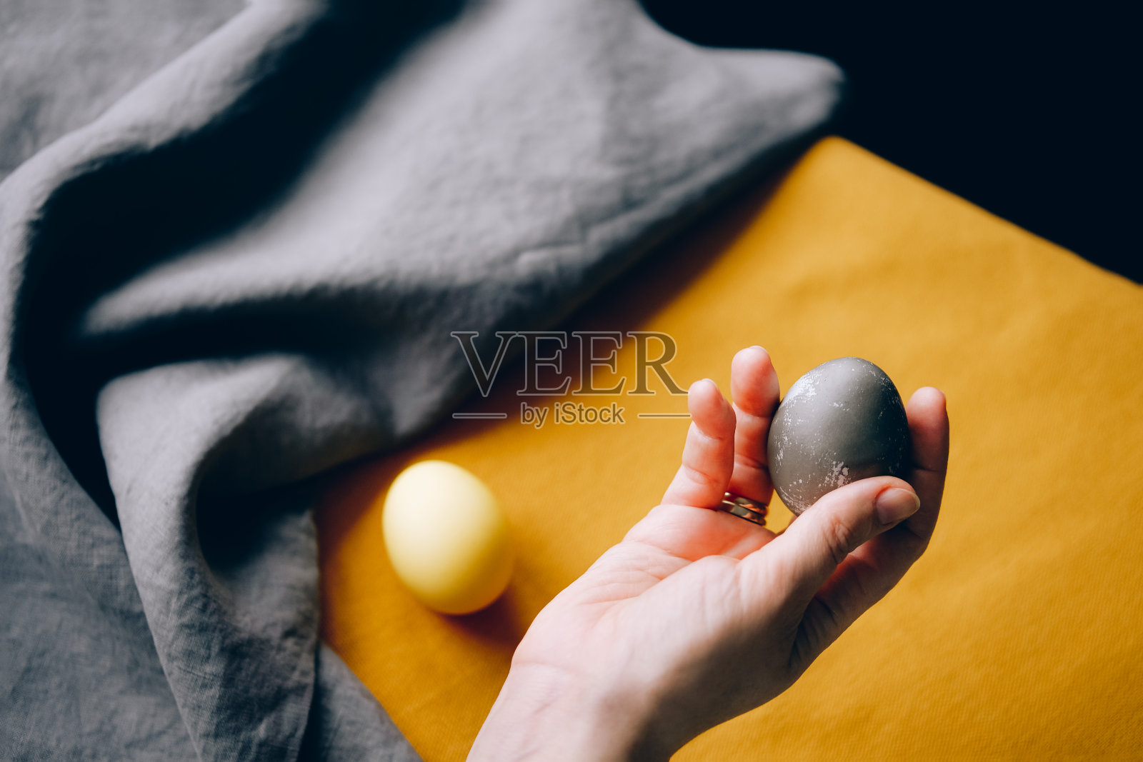 手握有机自然染色黄色和灰色复活节蛋。照片摄影图片