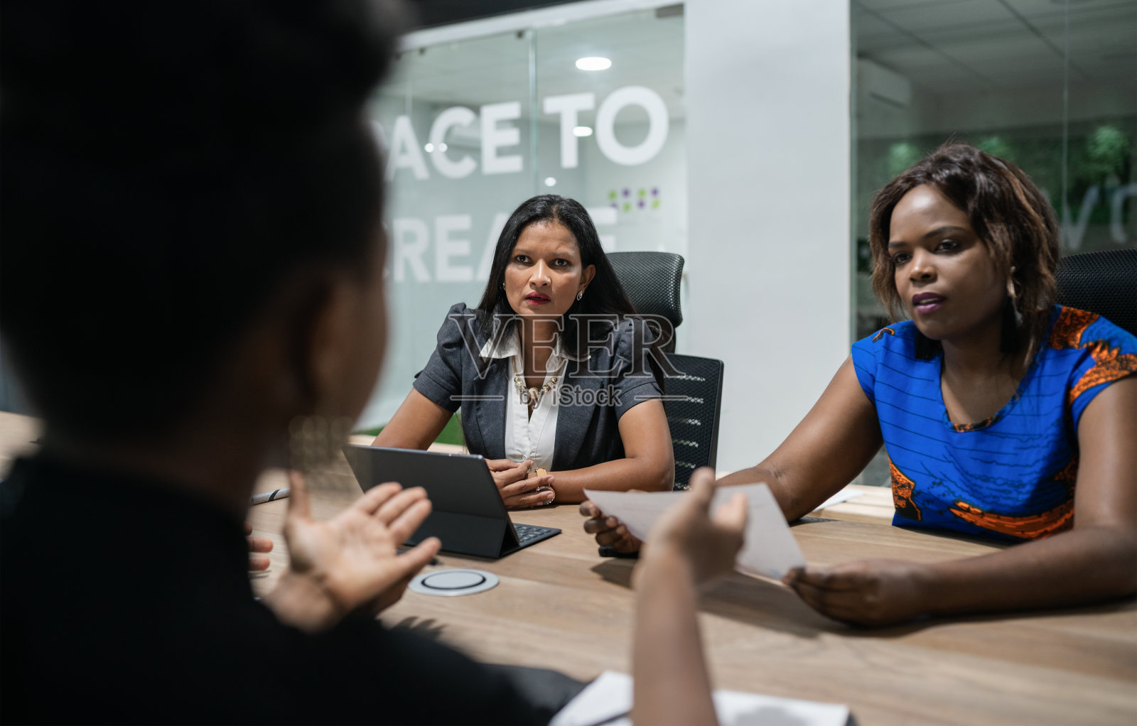 不同的商业女性与同事在会议室的桌子周围交谈照片摄影图片