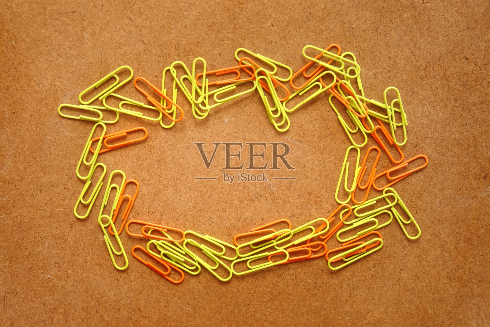 许多彩色(黄色和橙色)金属夹圈框架在棕色木桌为背景，有放置文字的拷贝空间照片摄影图片
