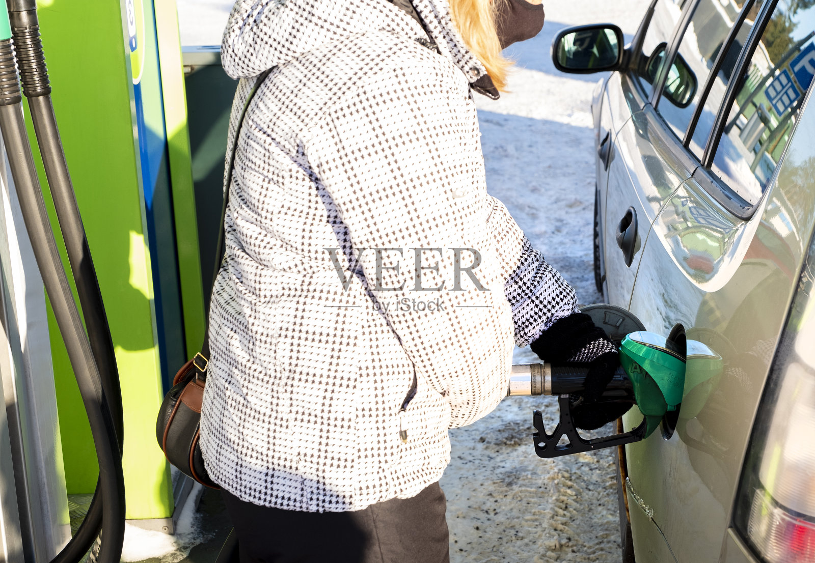 一个白人女孩在加油站给车加油，自助服务。照片摄影图片
