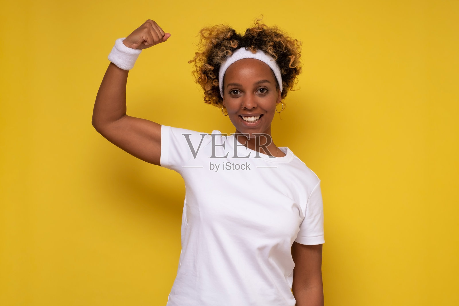 微笑强壮的年轻非洲妇女显示二头肌看着相机。照片摄影图片