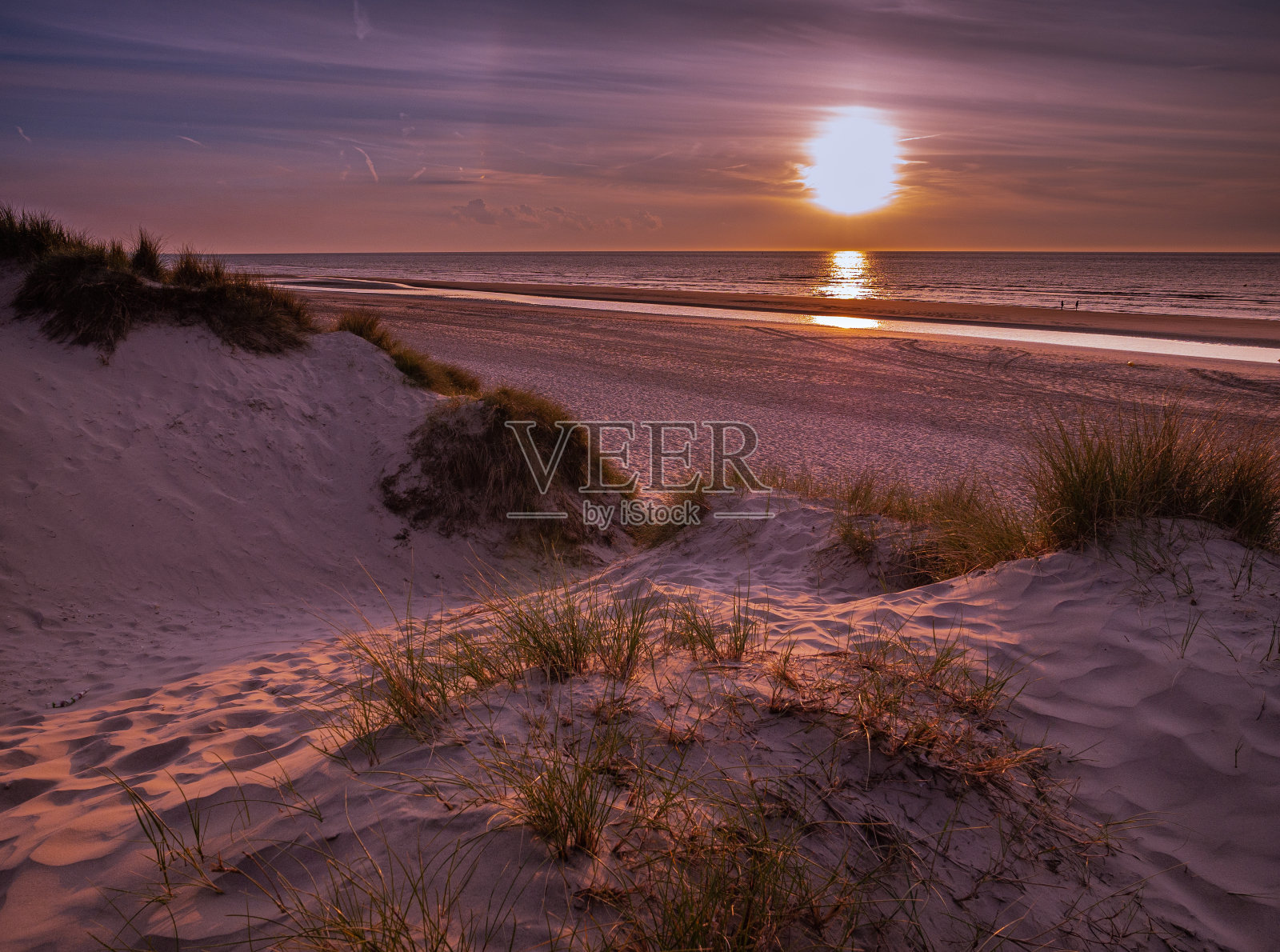 从马尔拉姆草覆盖沙丘向海滩前的一个彩色日落照片摄影图片