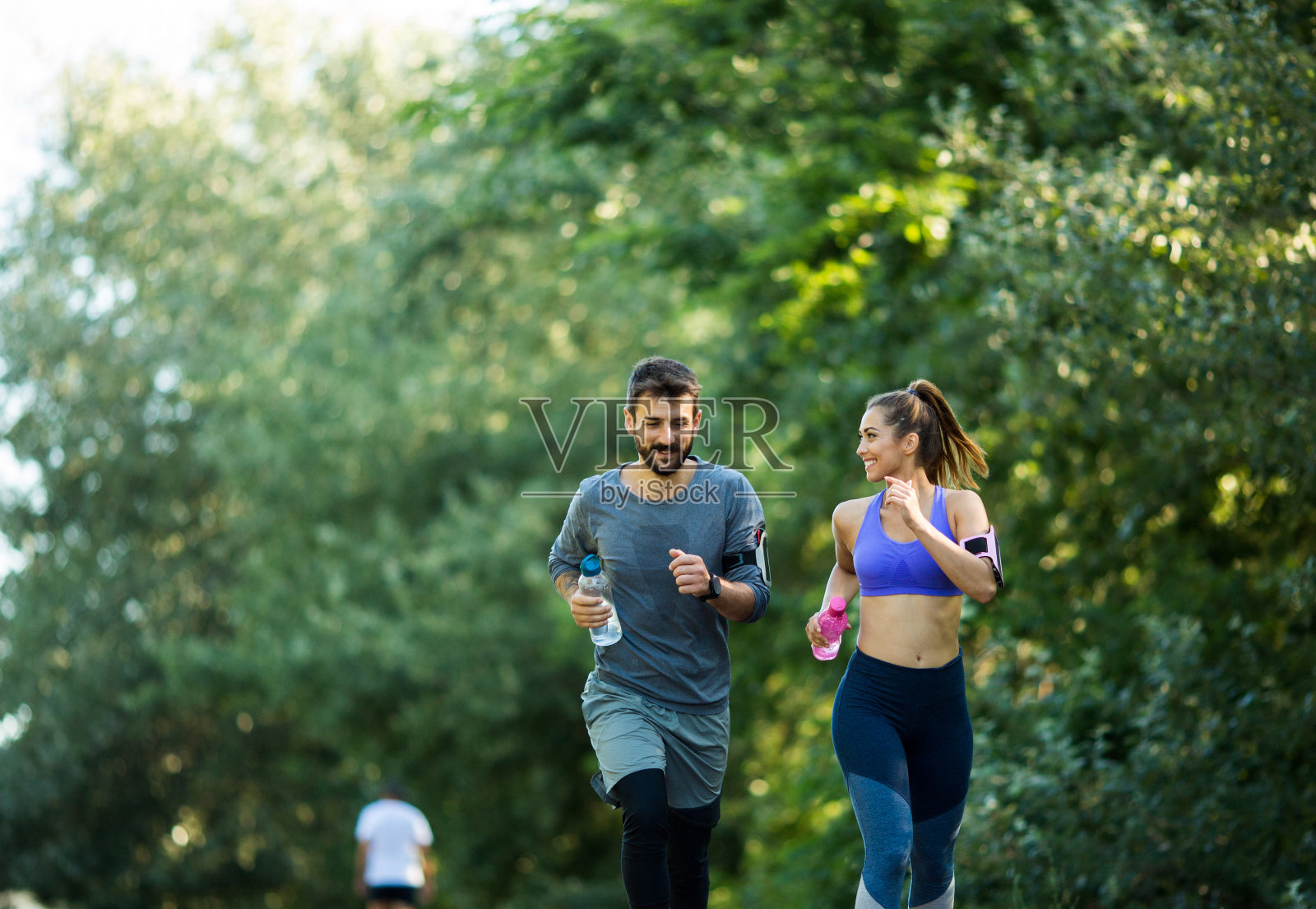 一对年轻夫妇在阳光明媚的日子慢跑。照片摄影图片