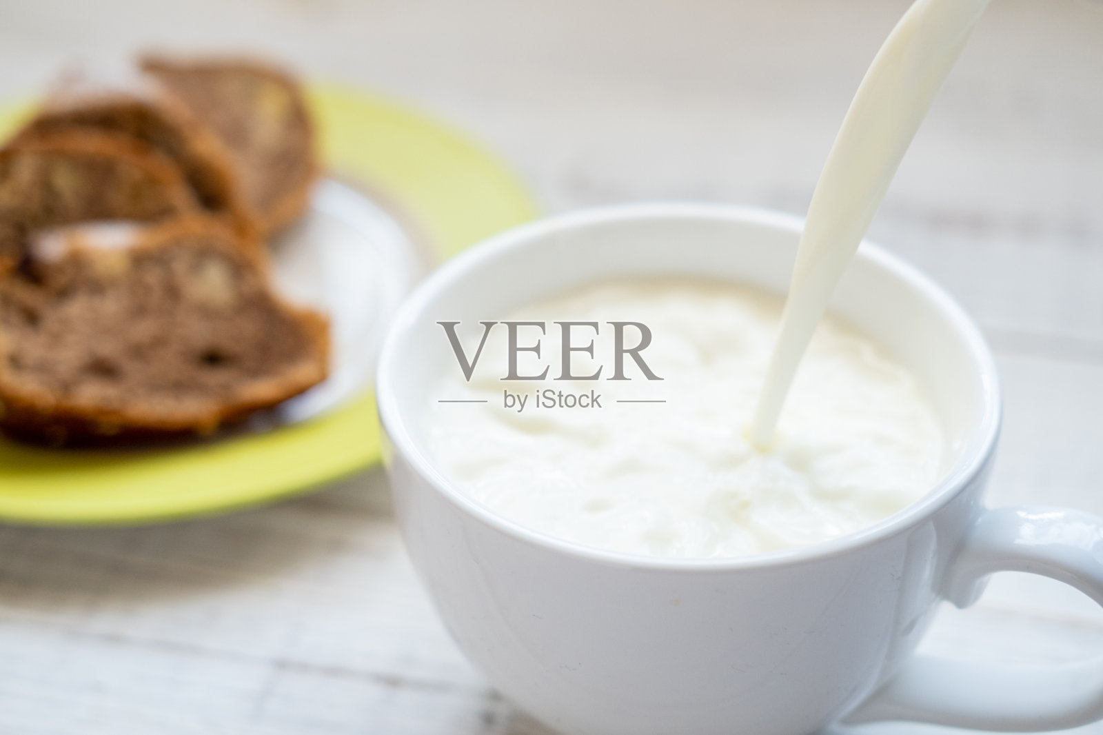 牛奶倒进杯子里。早餐配松饼。照片摄影图片