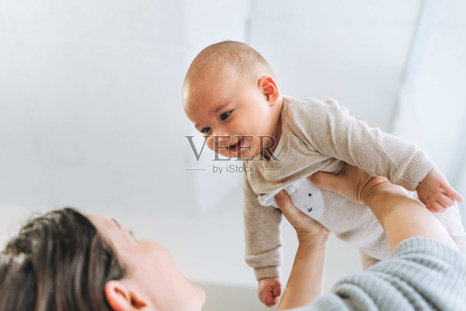 年轻的母亲在明亮的房间里玩可爱的宝贝男孩的手爱的情感照片摄影图片