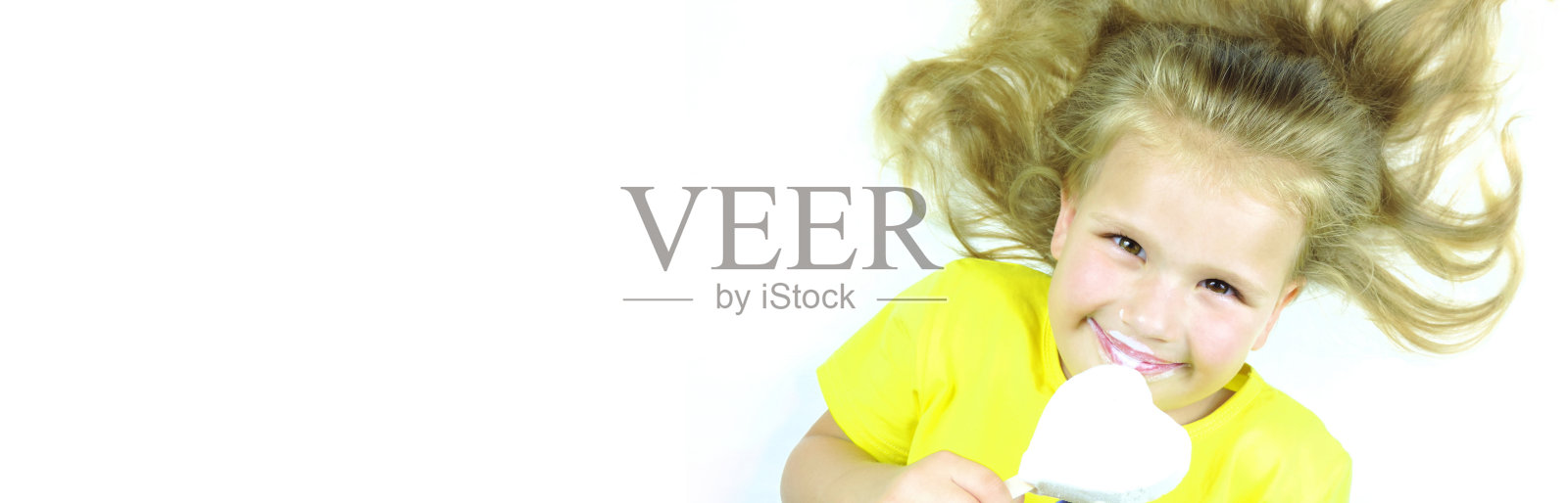 漂亮的小女孩正在吃白色背景上的心形冰淇淋照片摄影图片