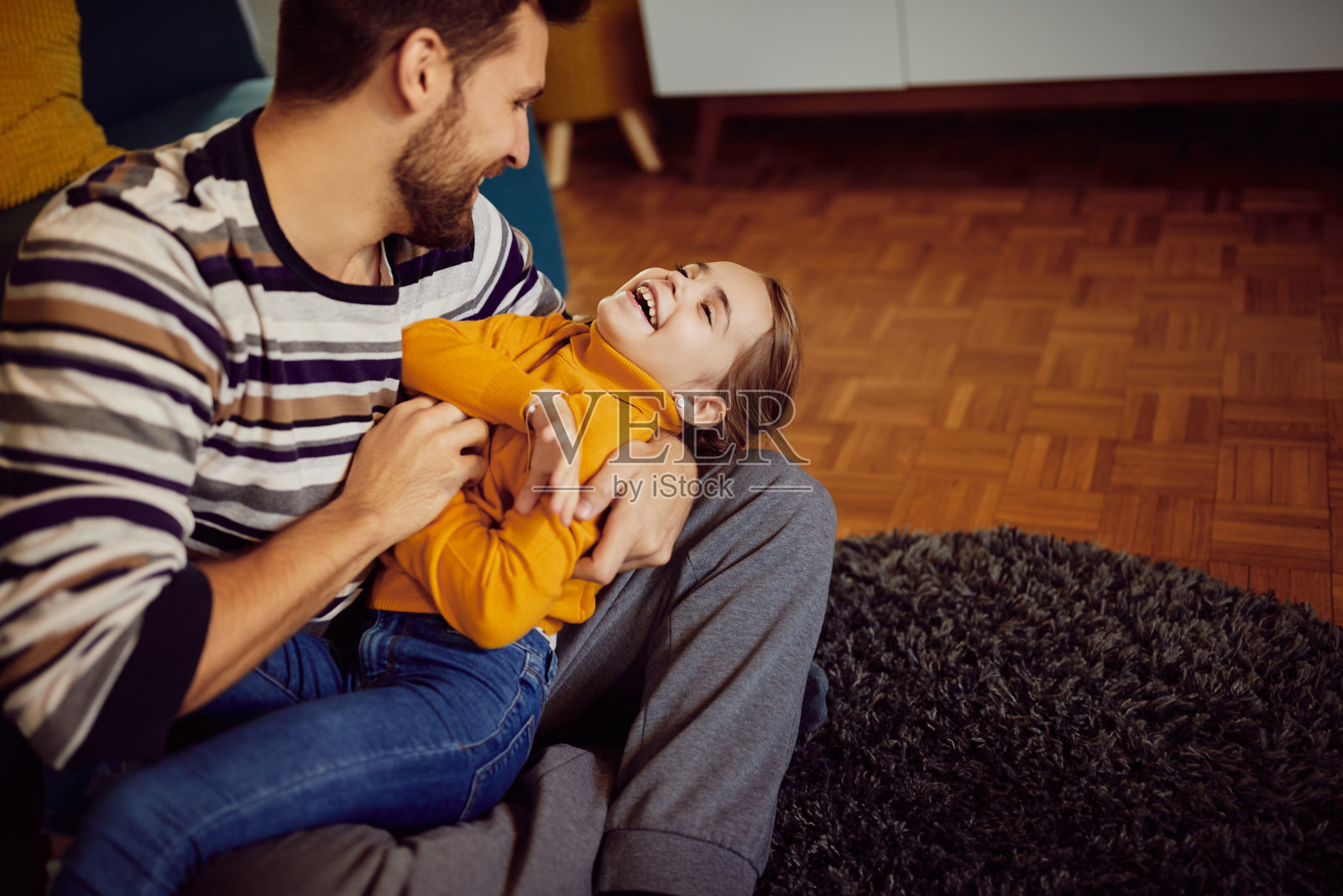 快乐的父亲给女儿挠痒痒，在家玩得开心。照片摄影图片