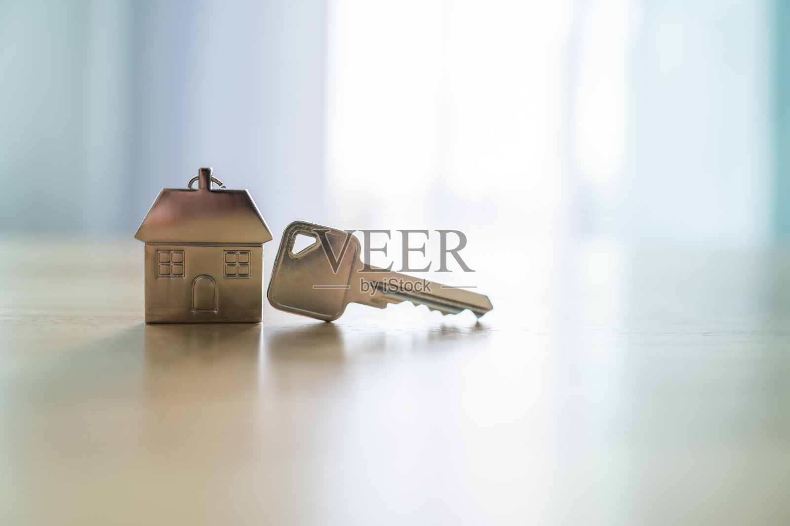 房间的木桌上有一把钥匙和一个钥匙链形状的房子。房地产投资和房屋抵押金融房地产概念照片摄影图片