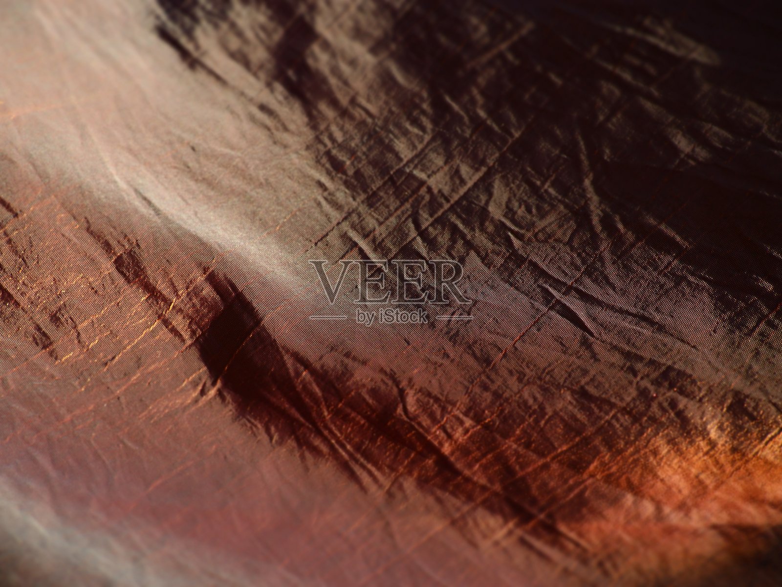 美丽的织物-塔夫绸，轻轻折叠成波浪。看起来像丝绸或锦缎的皱巴巴的材料。不同照明角度下的溢出和颜色渐变。缝衣服和窗帘用的布料照片摄影图片