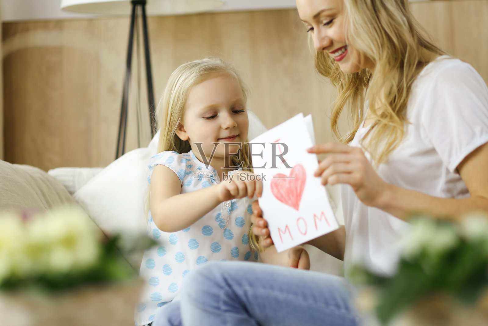 快乐的母亲的一天。小女儿向妈妈祝贺，并送给她一张画着心形的明信片。家庭和童年观念照片摄影图片