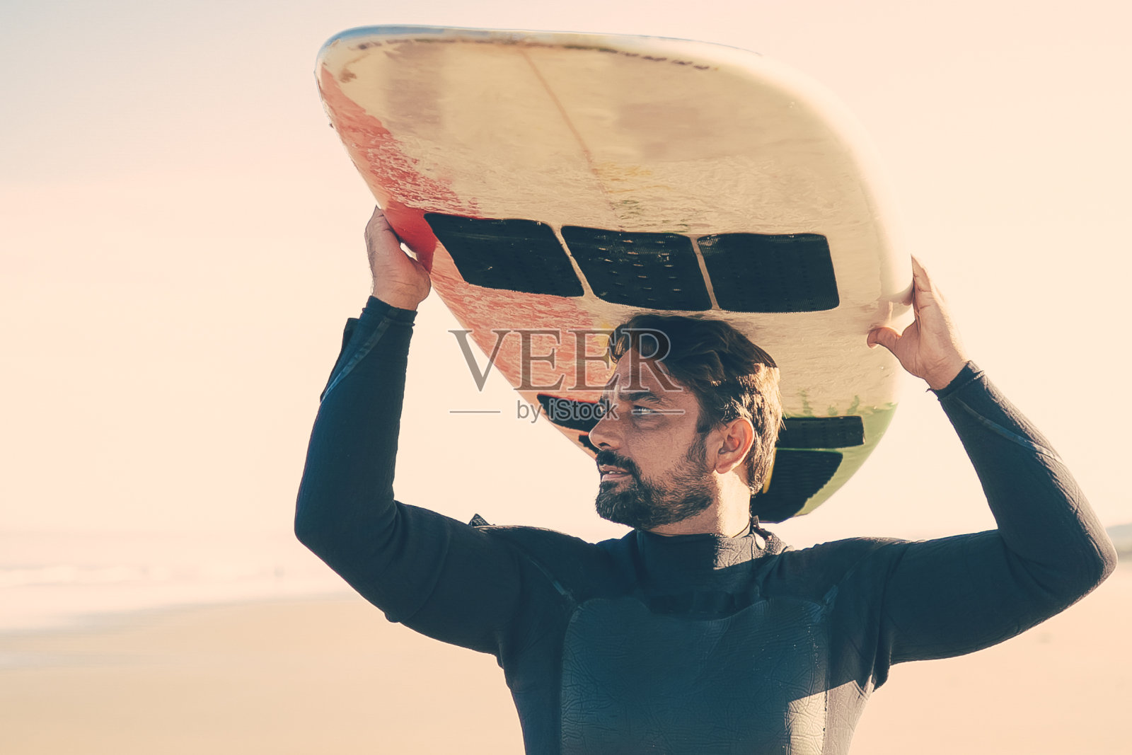 沉思的男性冲浪者把冲浪板顶在头上看着大海照片摄影图片
