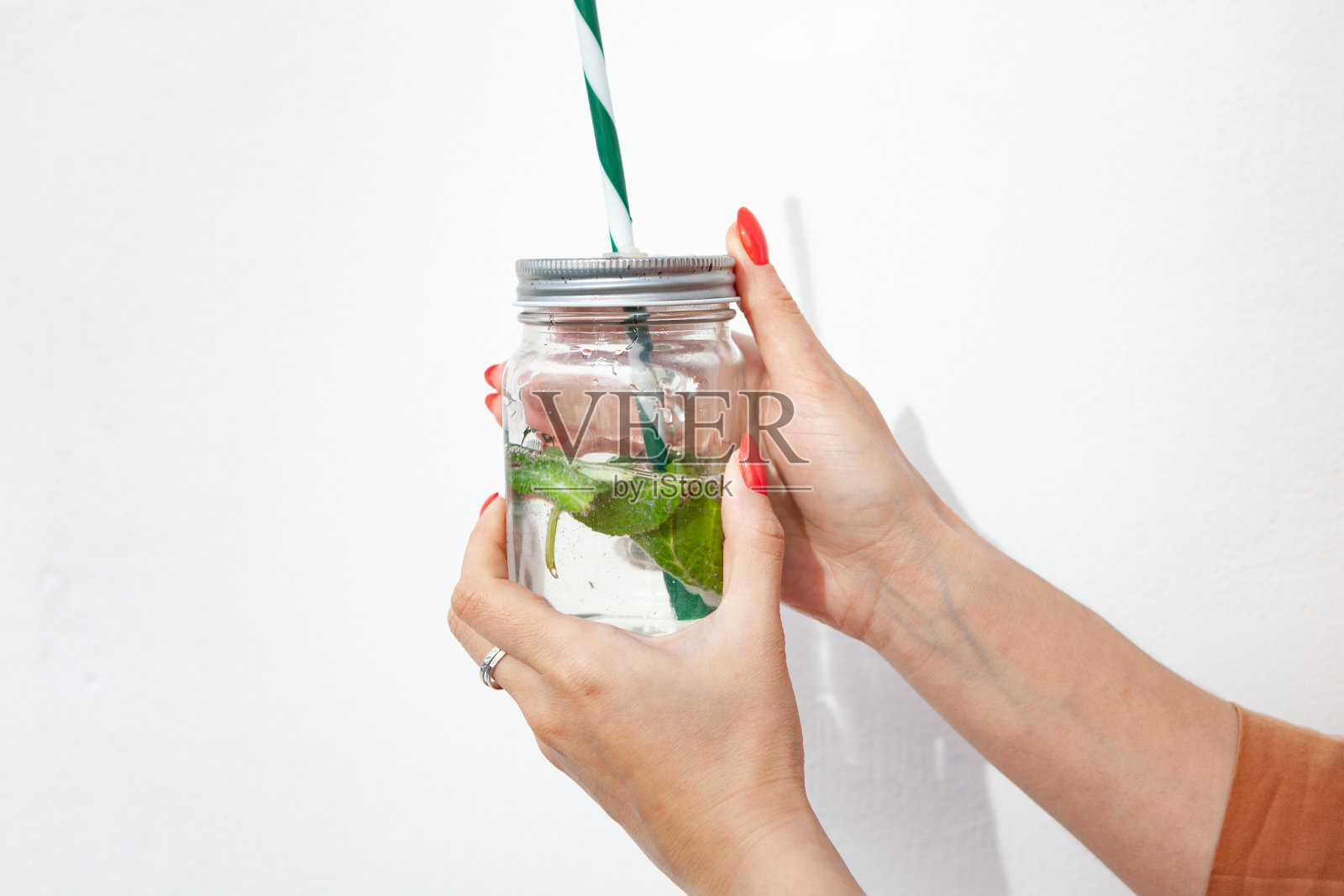 女孩手里拿着一个带吸管的杯子。在白色背景上。环保的概念照片摄影图片